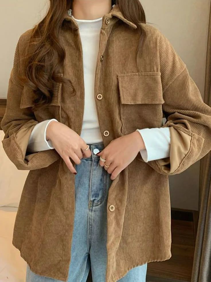 Woman wearing oversized brown corduroy shacket over white top with light wash jeans in casual fall style.