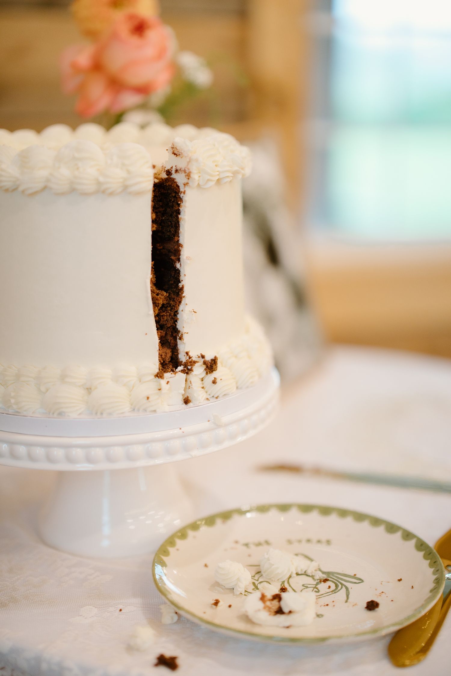 Sliced white wedding cake with chocolate interior on a white pedestal stand.
