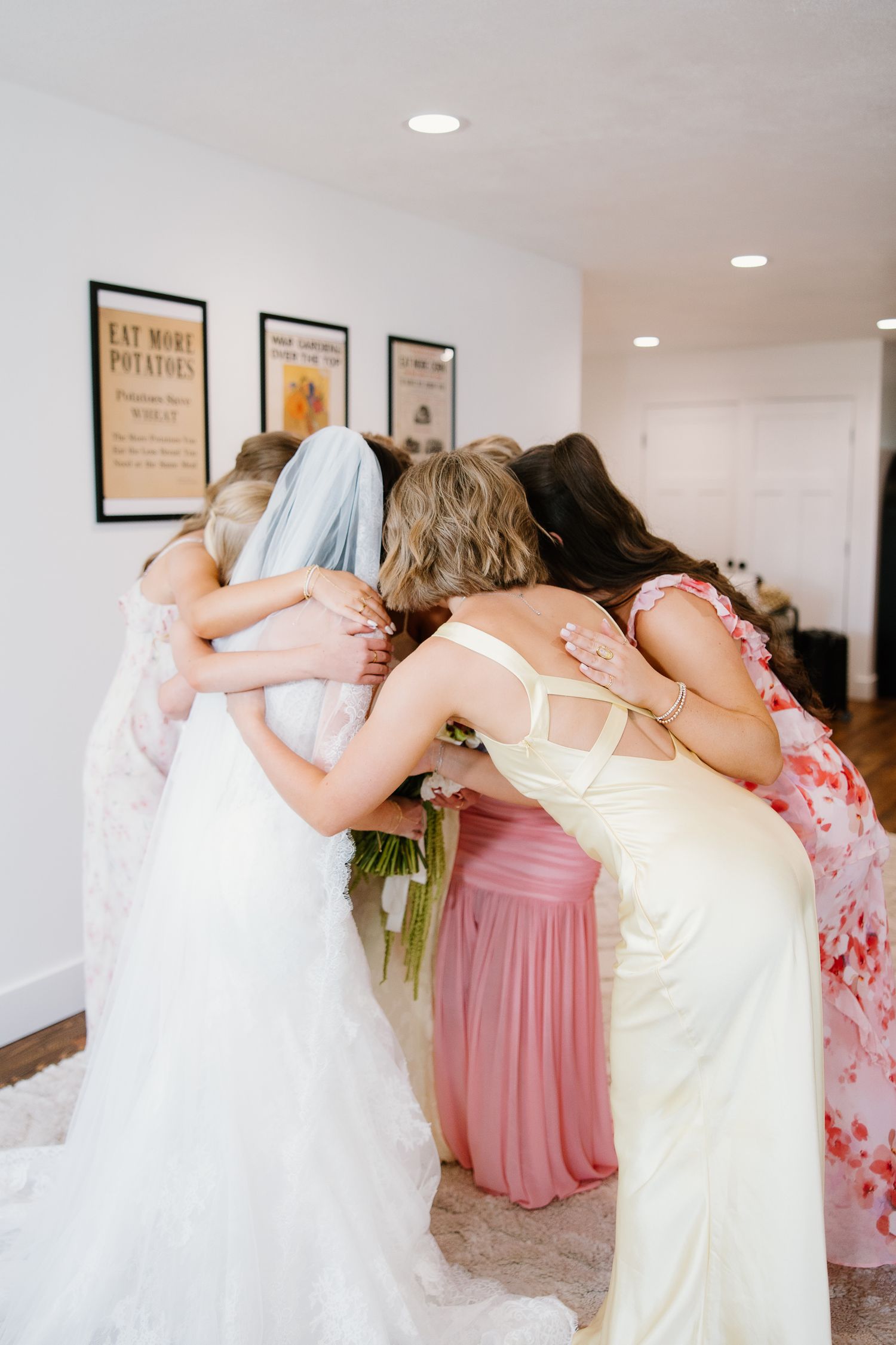 Bride and bridesmaids sharing a warm group hug before the wedding ceremony.