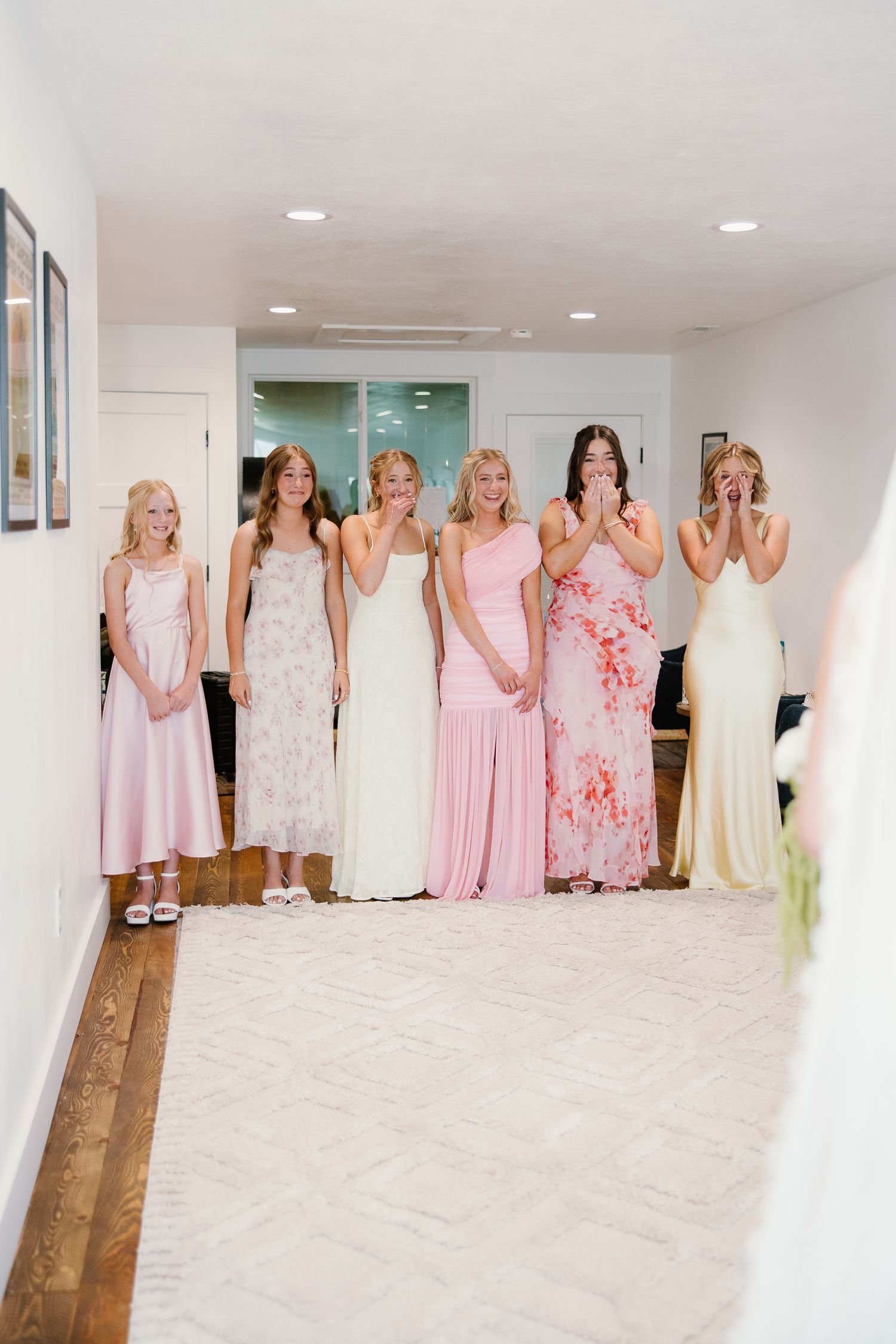 Bridesmaids in pink dresses react emotionally seeing the bride for the first time.