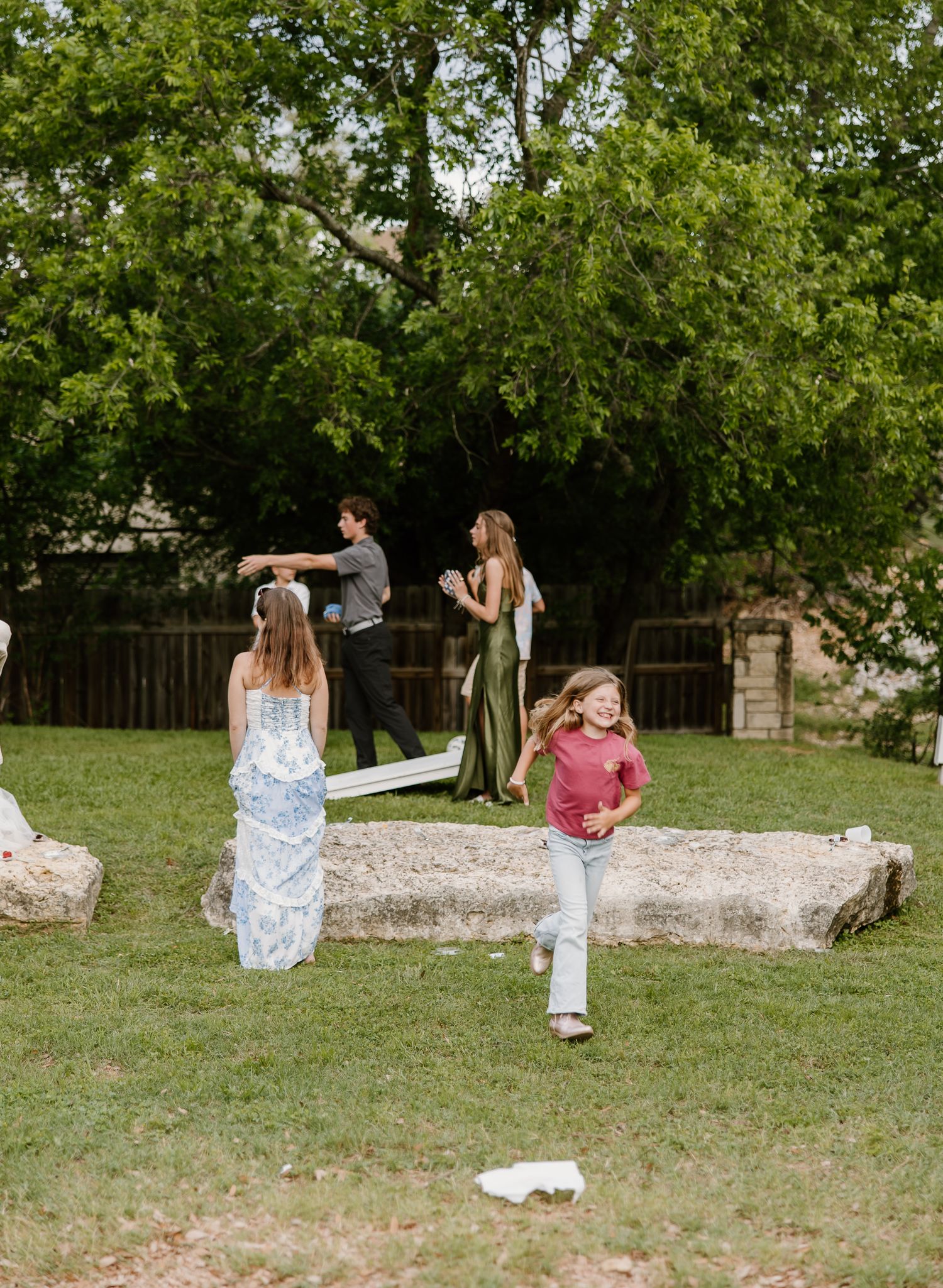 Children and guests playing outdoors on green lawn at a relaxed rustic wedding reception.