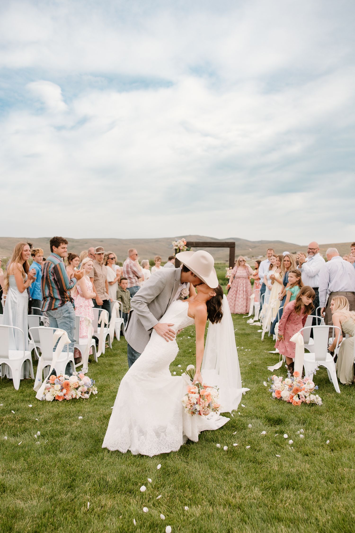 Bride and groom share first kiss as newlyweds at outdoor western wedding ceremony.