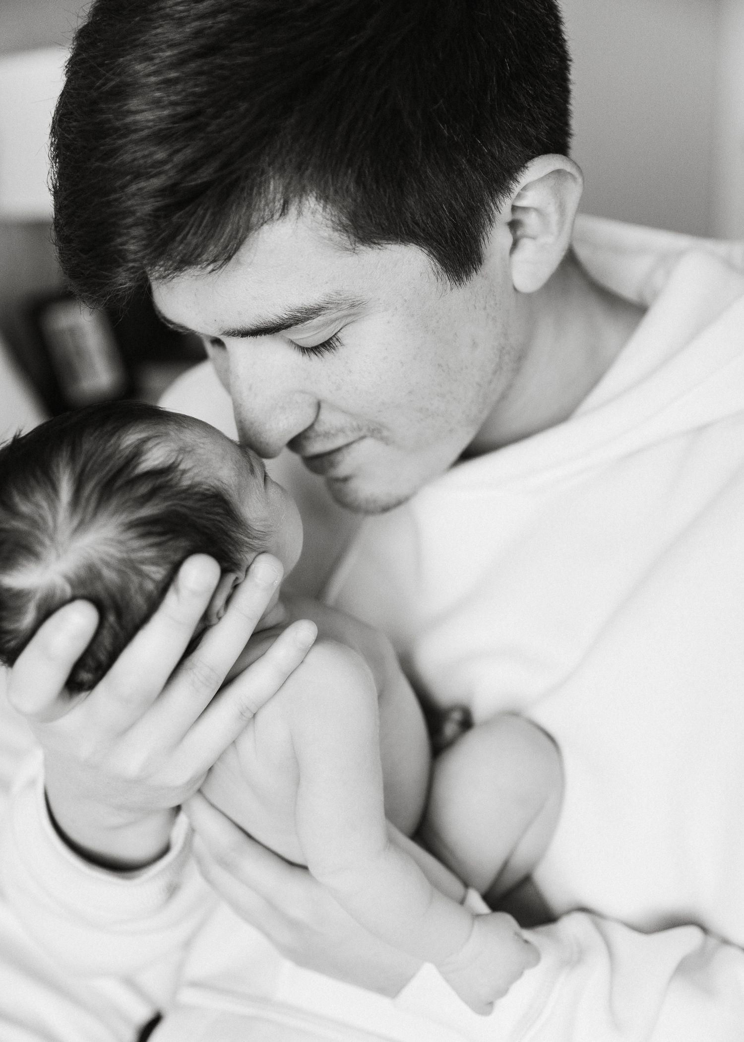 Black and white photo of a father tenderly holding his newborn baby close.