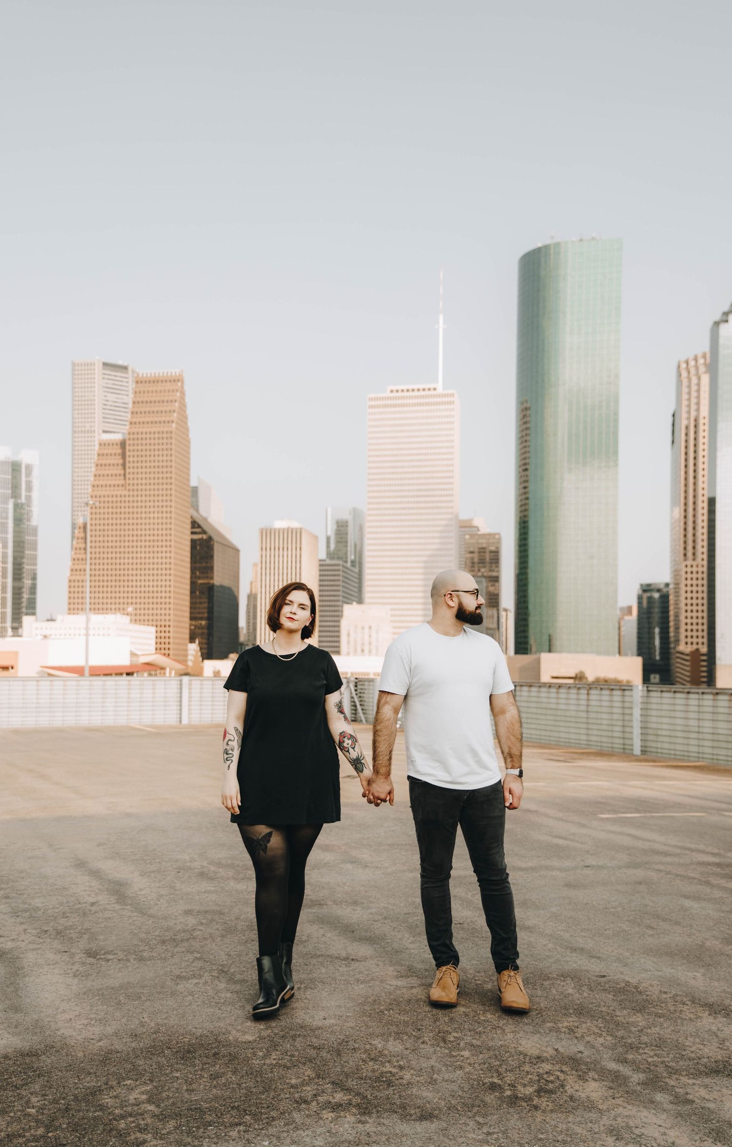 Couple holding hands on a rooftop with Houston city skyline in the background.