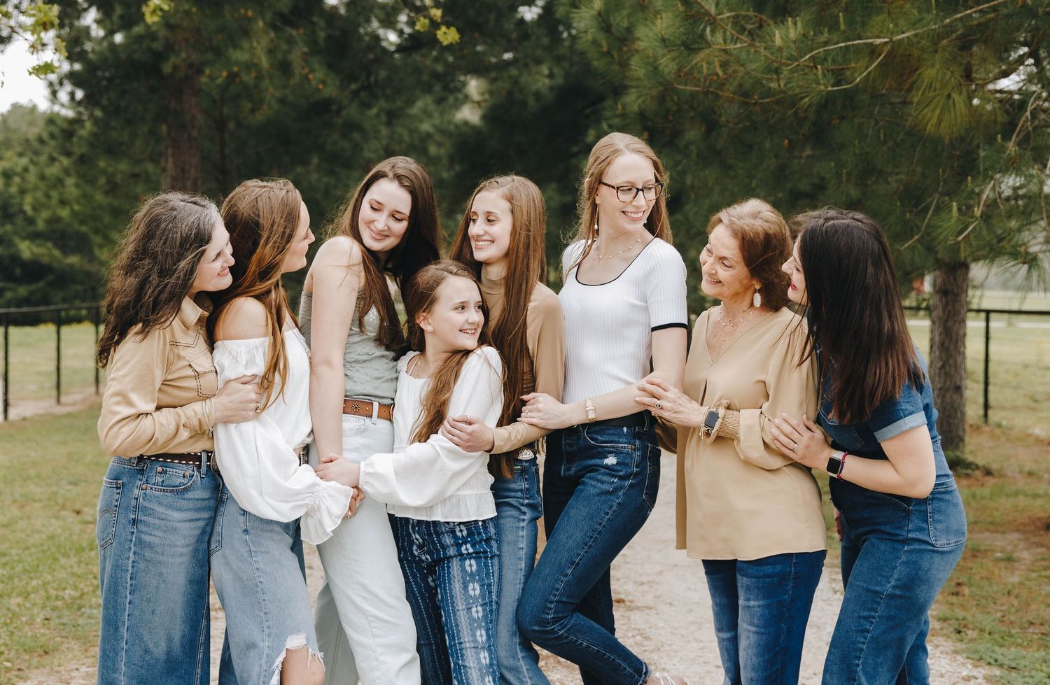 Group of eight young women laughing and embracing during an outdoor photo session.