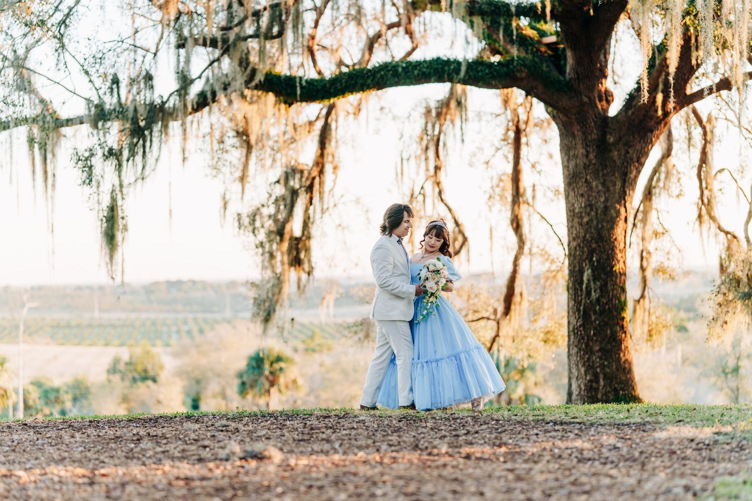 Couple in a blue ball gown and white suit dancing under a moss-draped oak at Bok Tower Gardens, Lake Wales, Florida