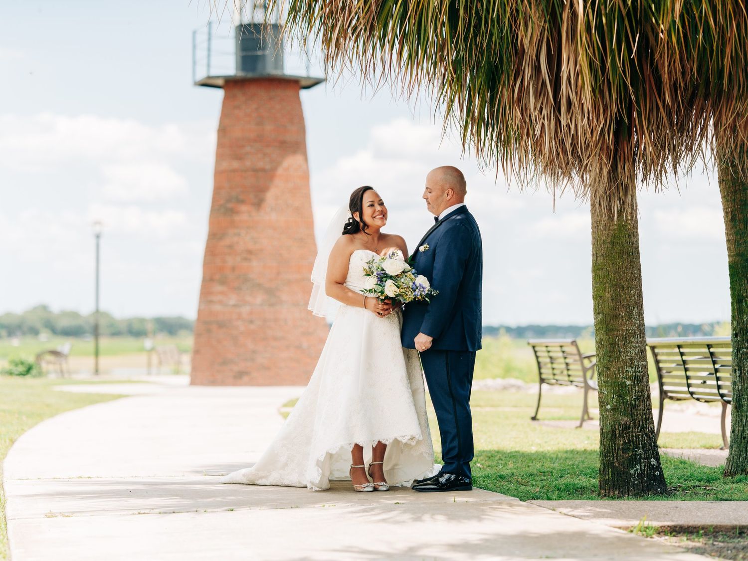 Bride and groom under a palm tree by the lighthouse at Kissimmee Lakefront Park, Kissimmee, Florida wedding photography