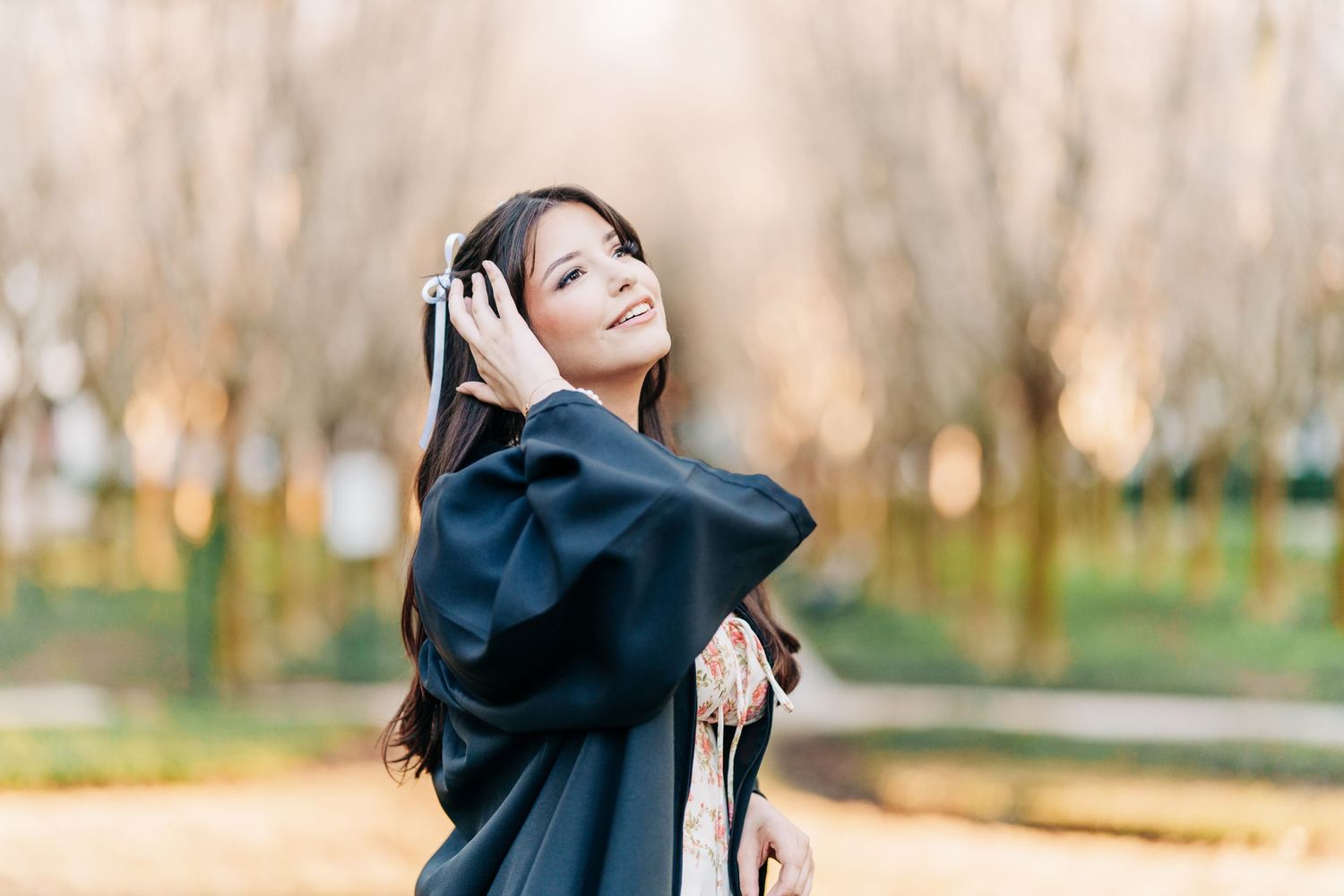 A person in a black hoodie enjoying music through headphones while standing in a sunlit autumn park.