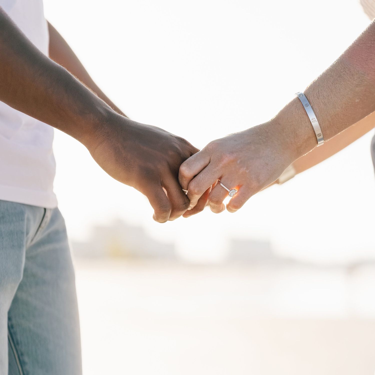 Close-up of a couple holding hands with engagement rings on Siesta Key Beach in Sarasota, Florida