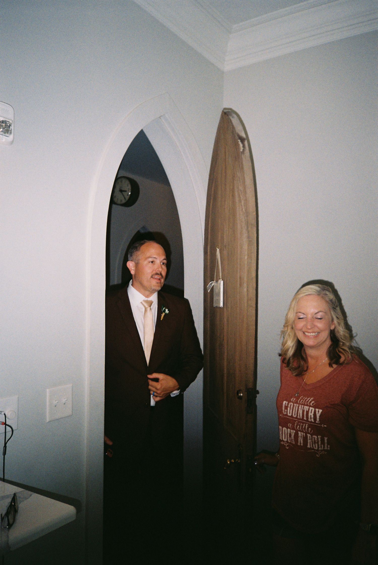 People playfully peeking around doorways in a dimly lit hallway creating a fun candid moment.