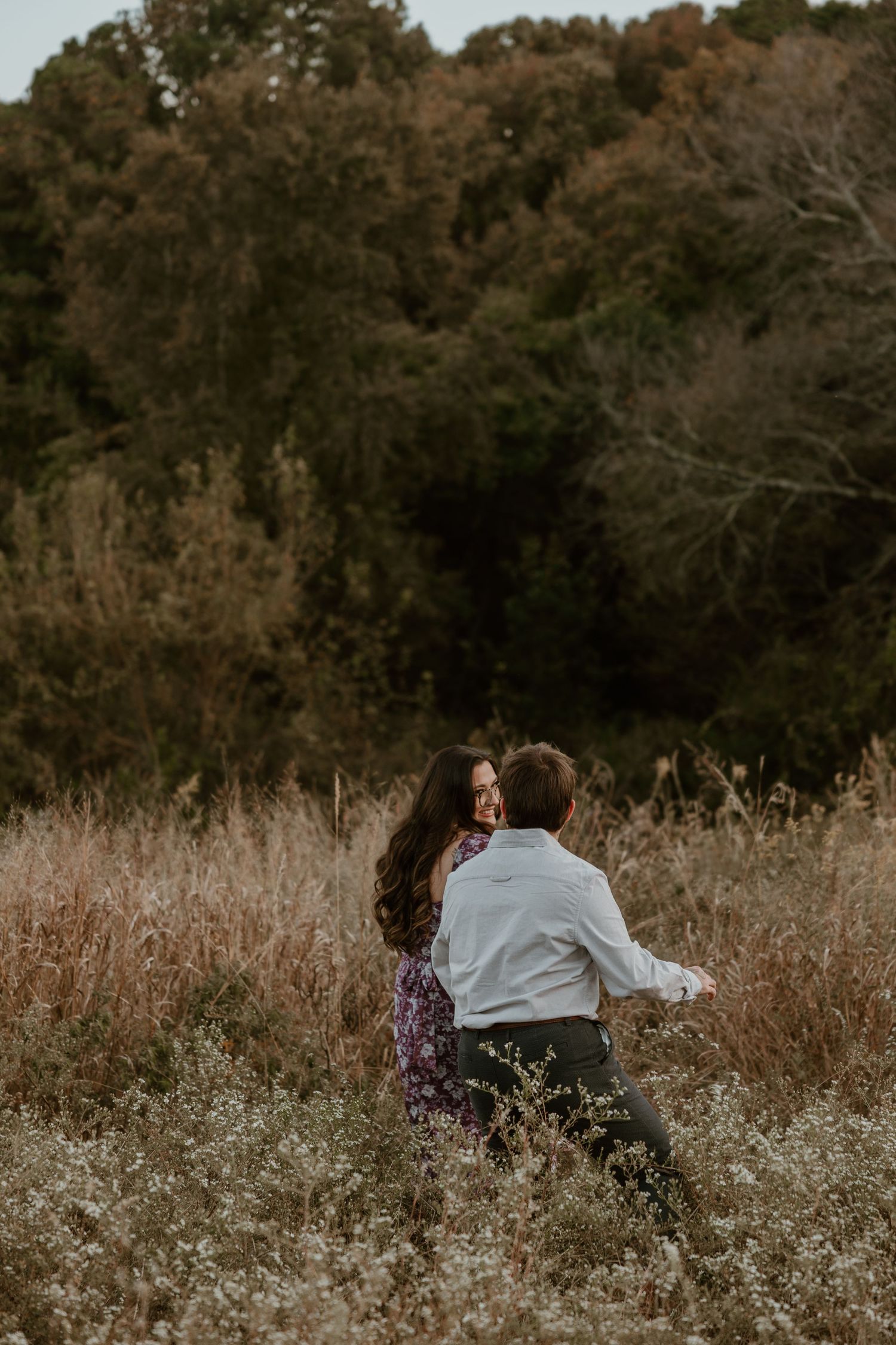 Couple sharing an intimate moment together in a rustic field with tall dried grasses.