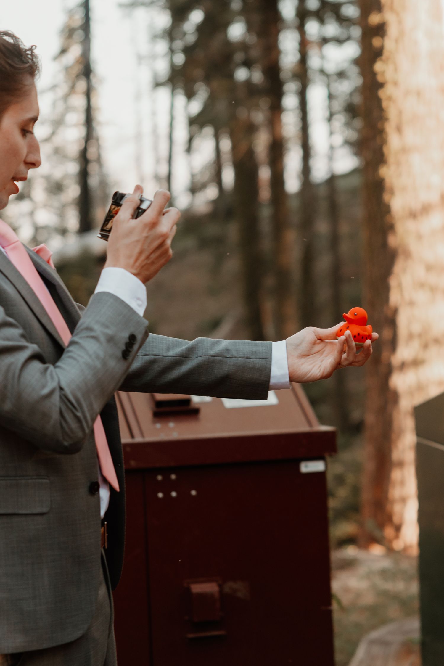 Wedding detail shot of hands holding a ring box in front of a rustic mailbox.