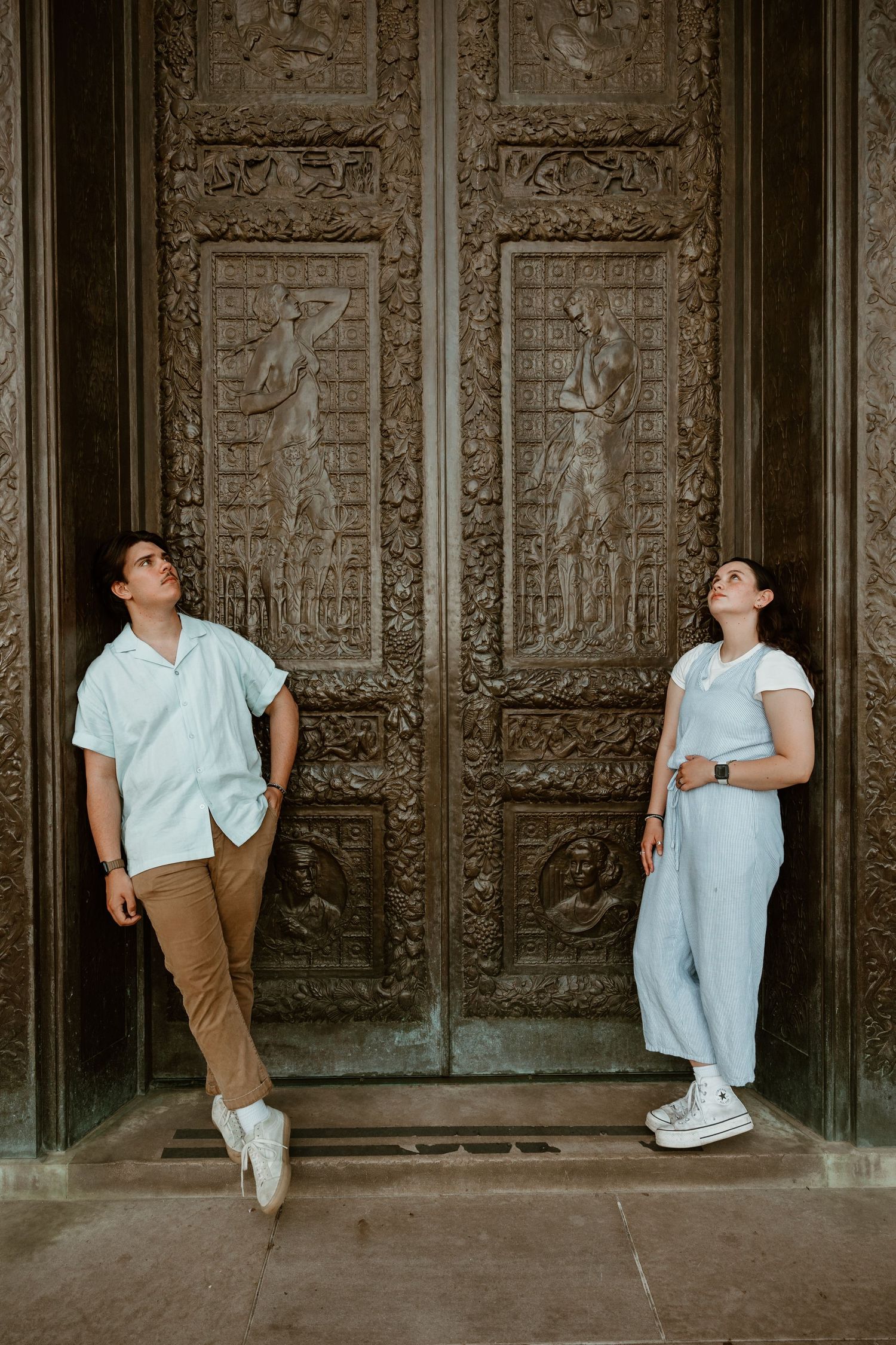 People posing against ornate carved wall panels in vintage architectural setting.