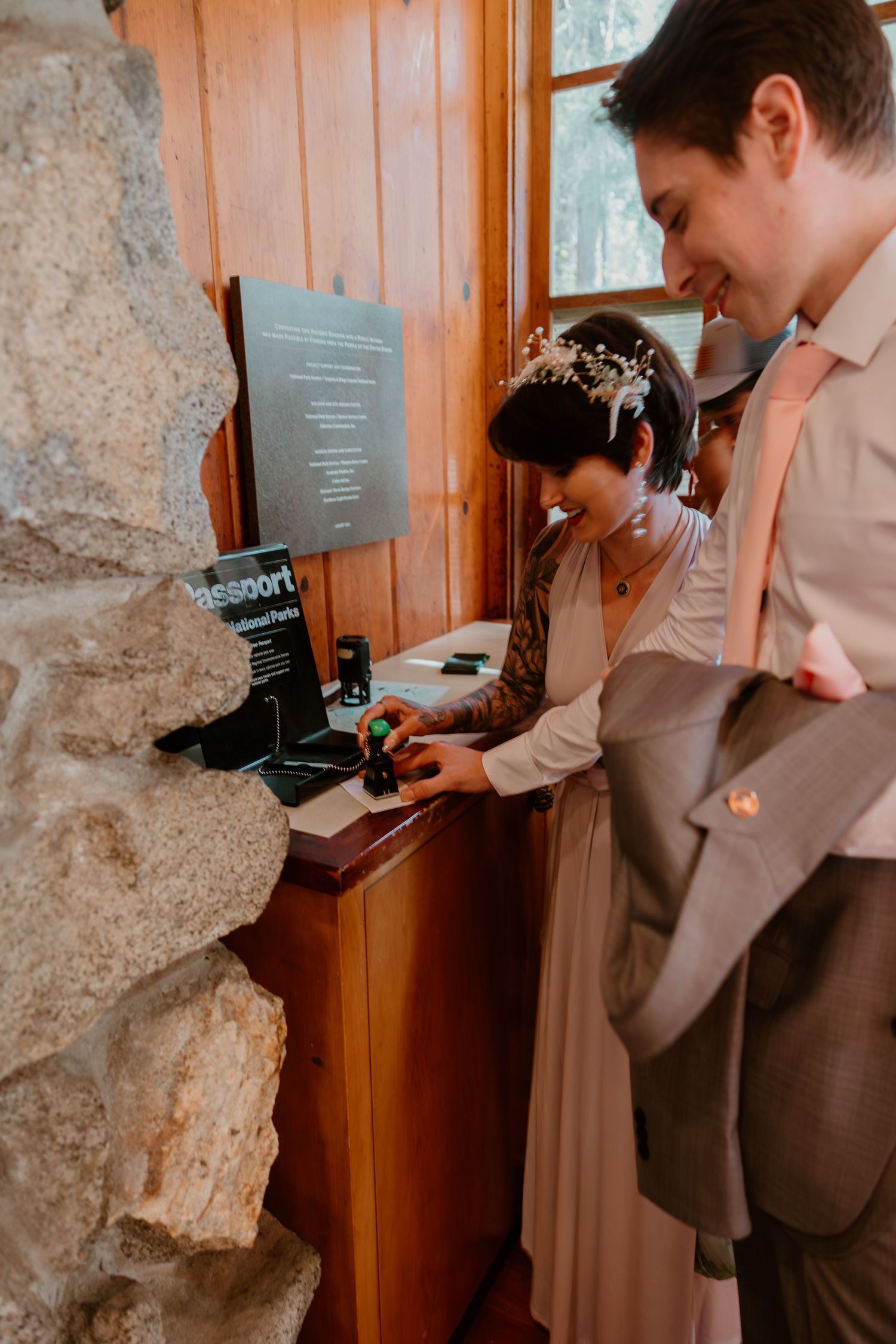 Couple reading information displayed on a rustic wooden sign in a national park.