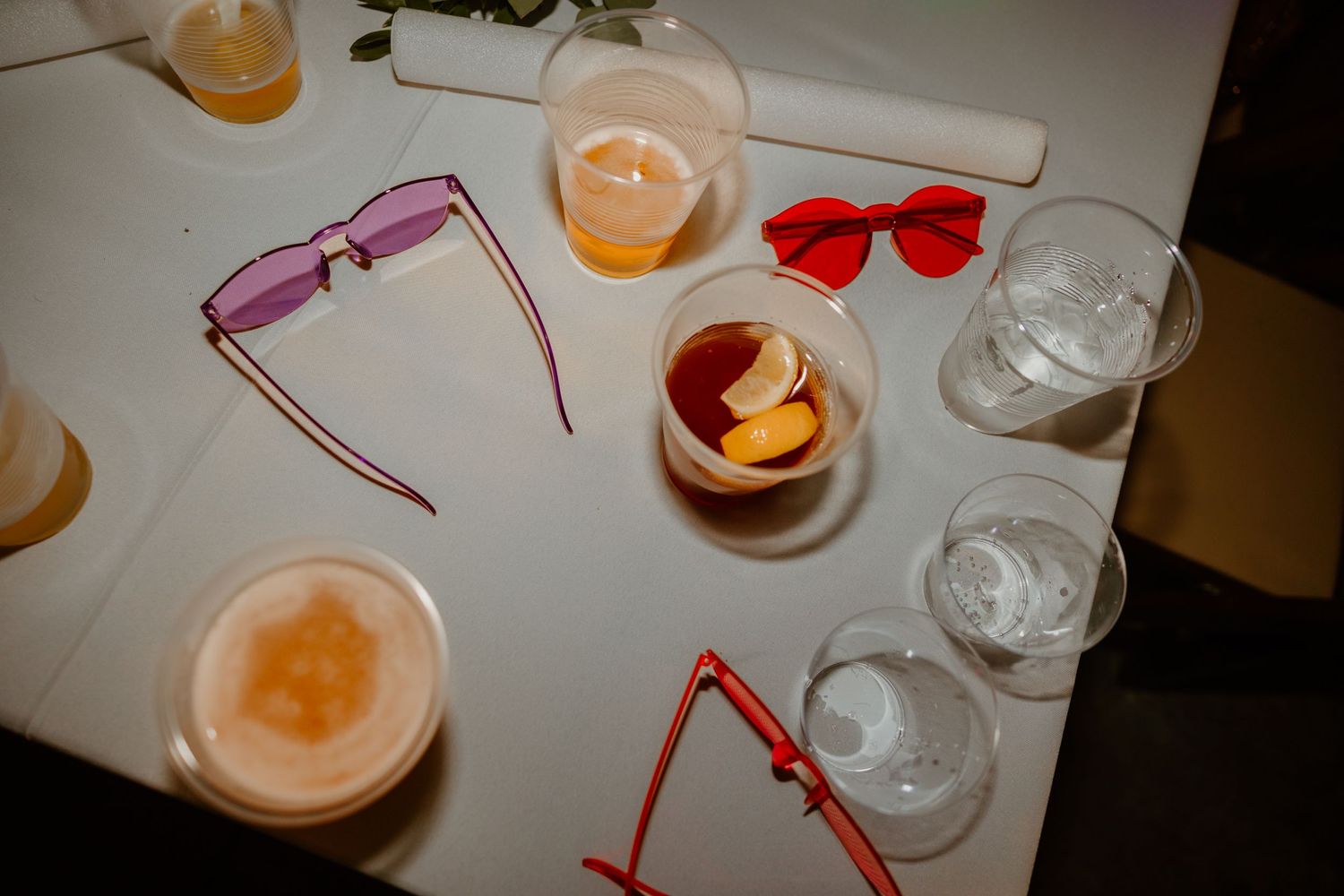 Wedding reception table with colorful drinks and sunglasses as party favors.