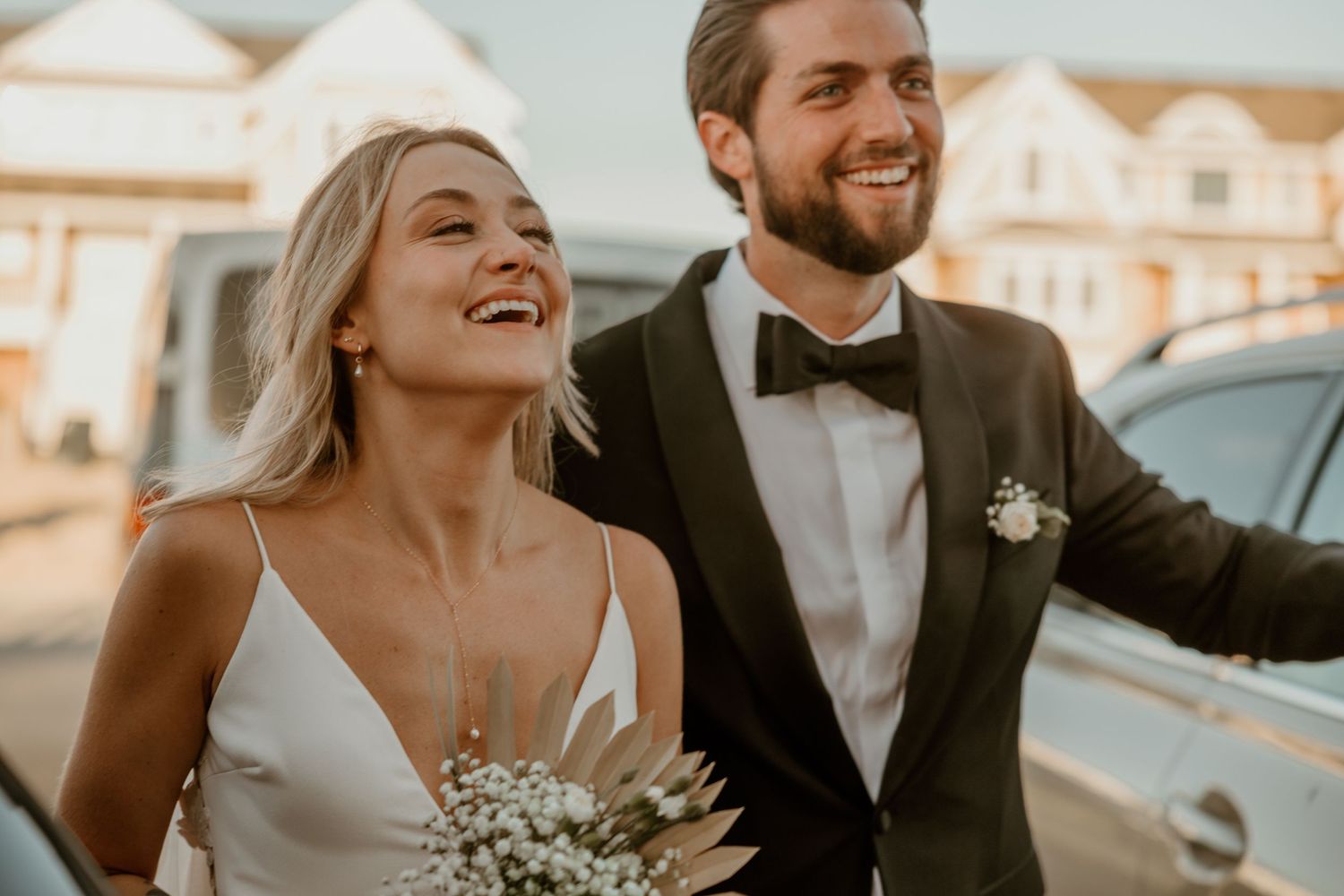 A joyful candid moment captured of newlyweds laughing in formal attire.
