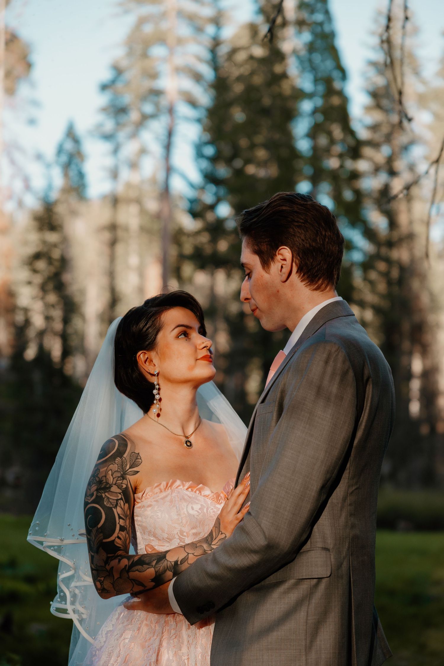 Wedding couple shares intimate moment in forest clearing during golden hour.