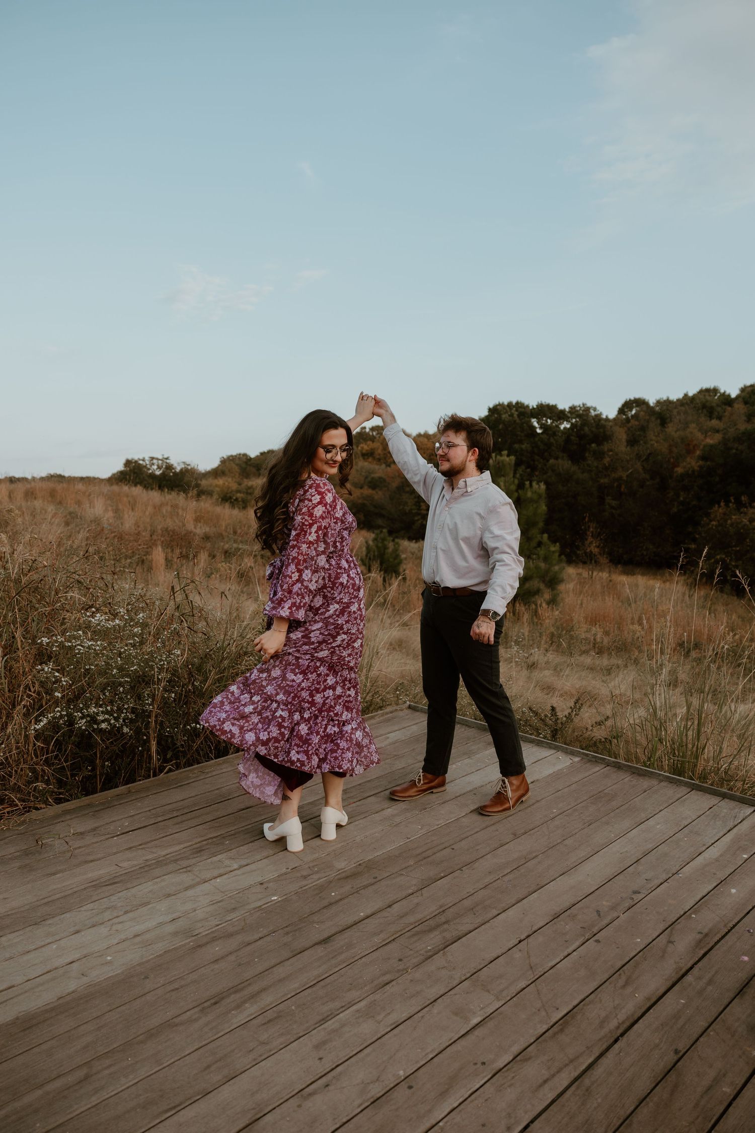 Playful couple interacting on wooden deck surrounded by autumn field landscape.