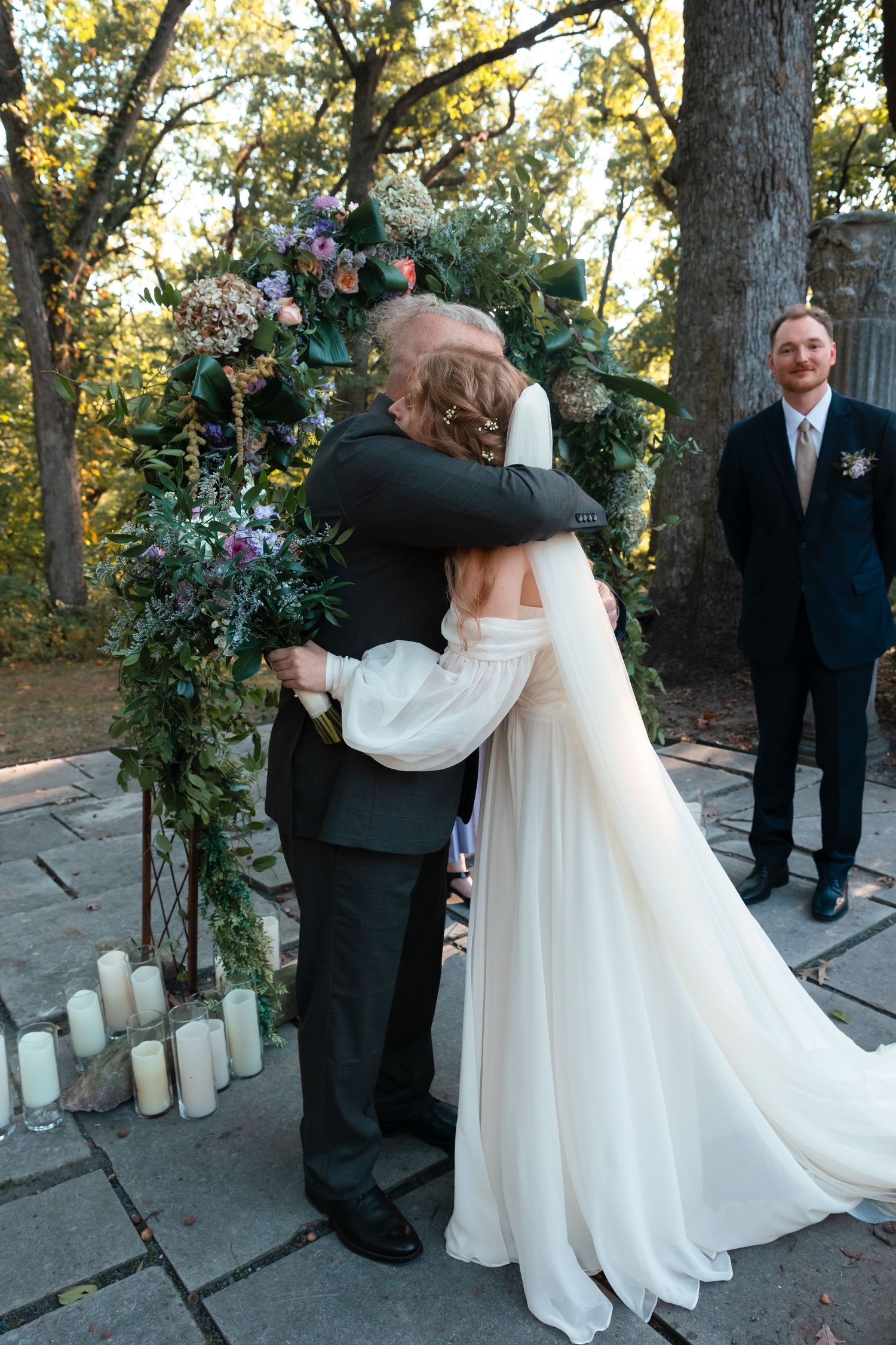 Outdoor wedding sequence showing couple embracing near floral arch and candles at sunset.