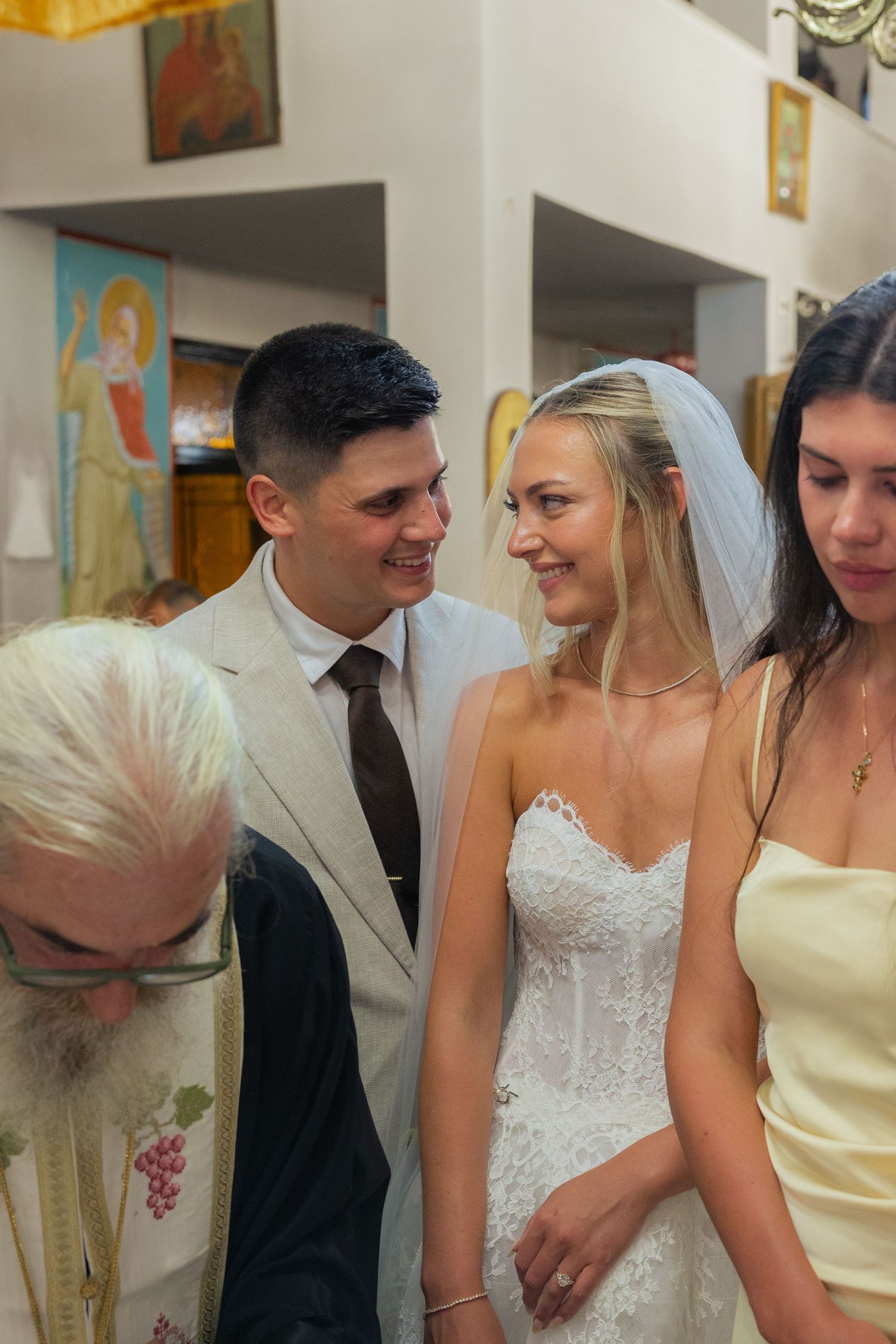 Bridal party members share joyful moments during a wedding ceremony in a church setting.
