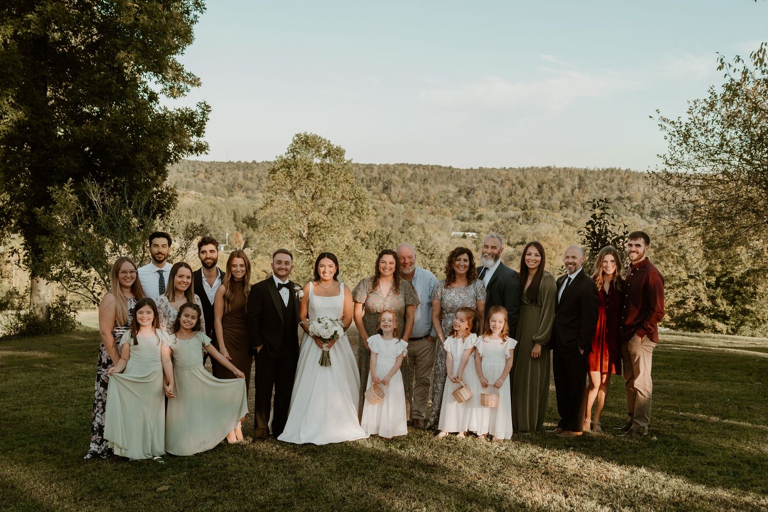 Wedding party poses together on lawn during golden hour.