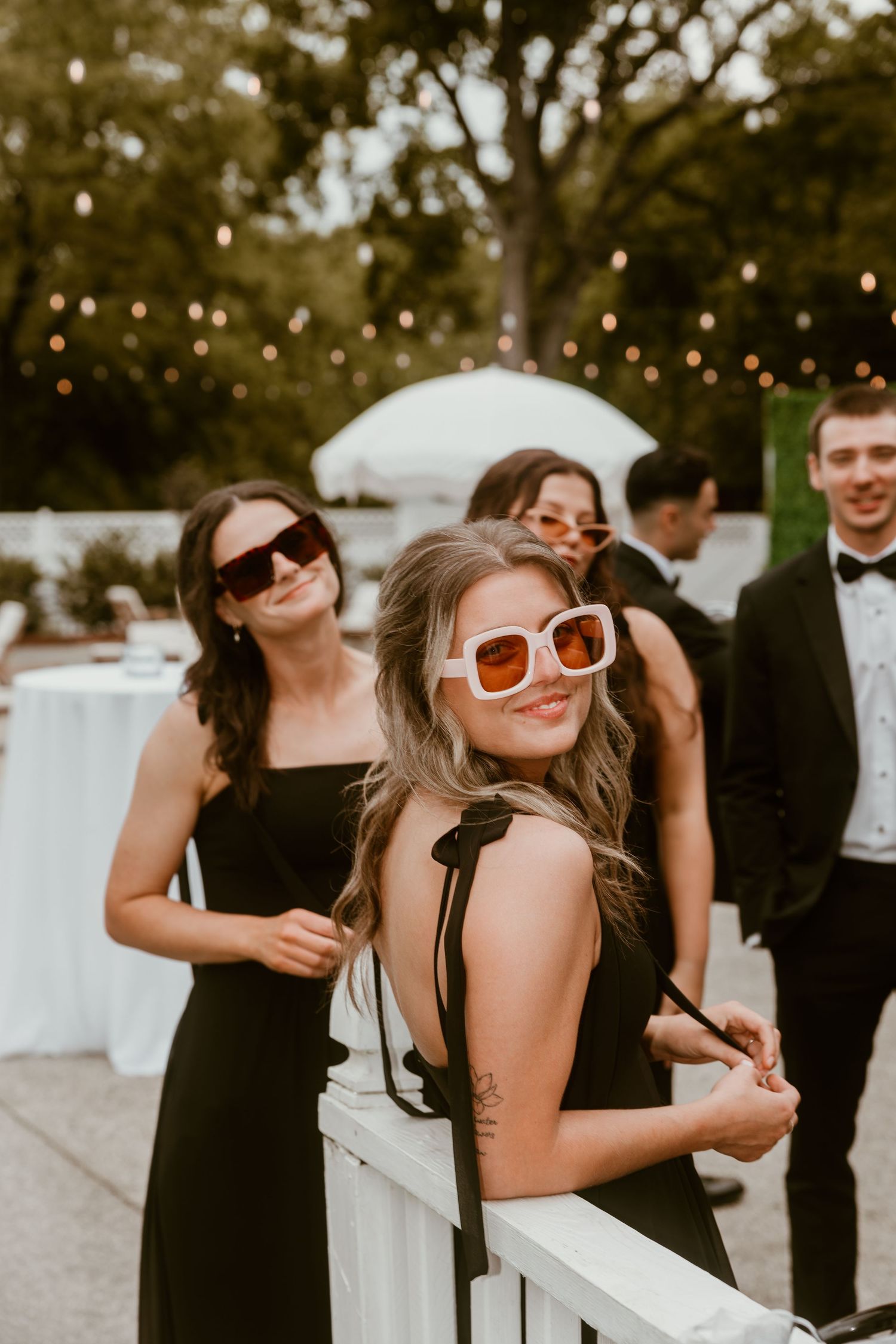 Wedding guests enjoying outdoor reception with string lights and festive atmosphere.