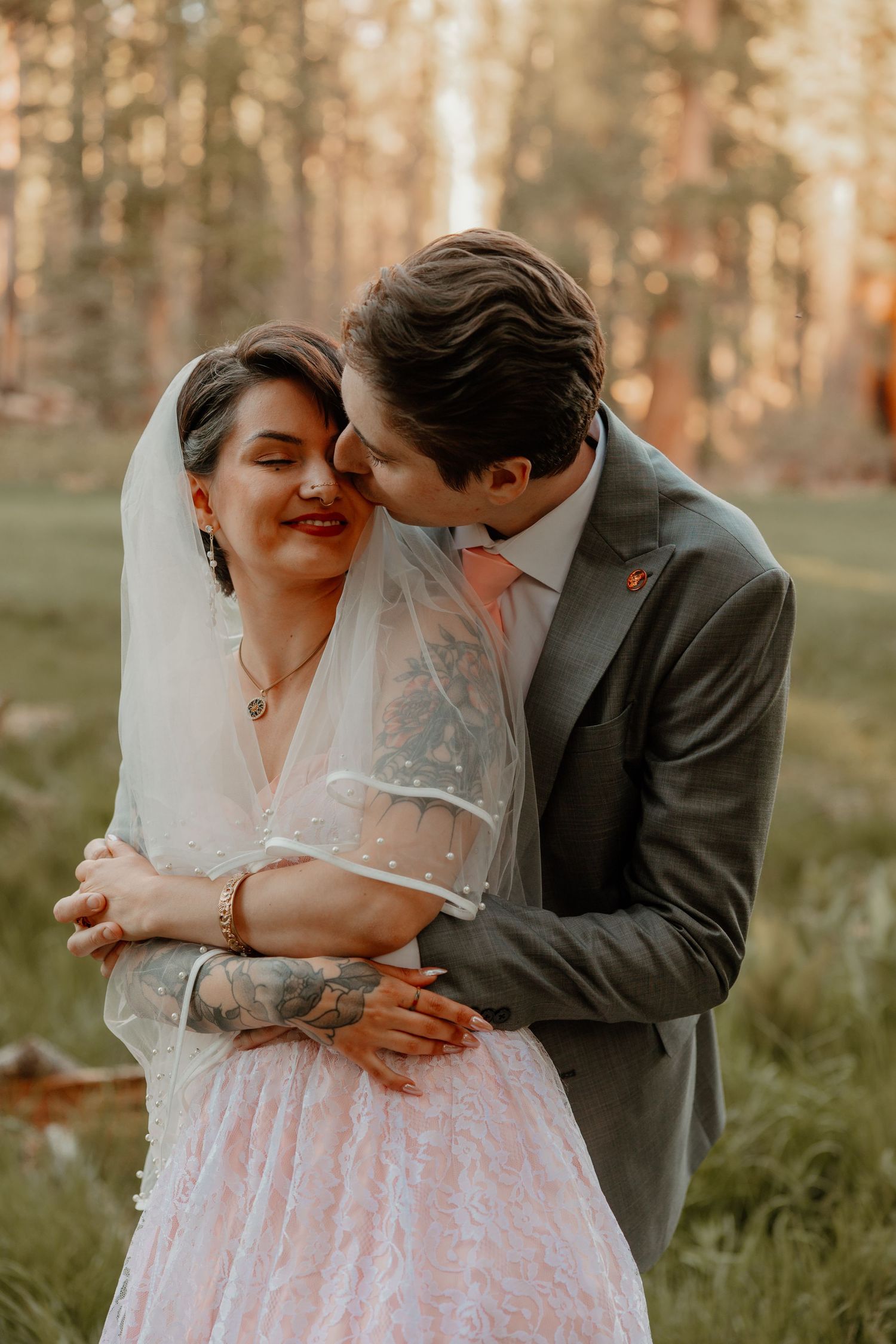 Romantic moment between newlyweds in rustic forest setting during sunset.
