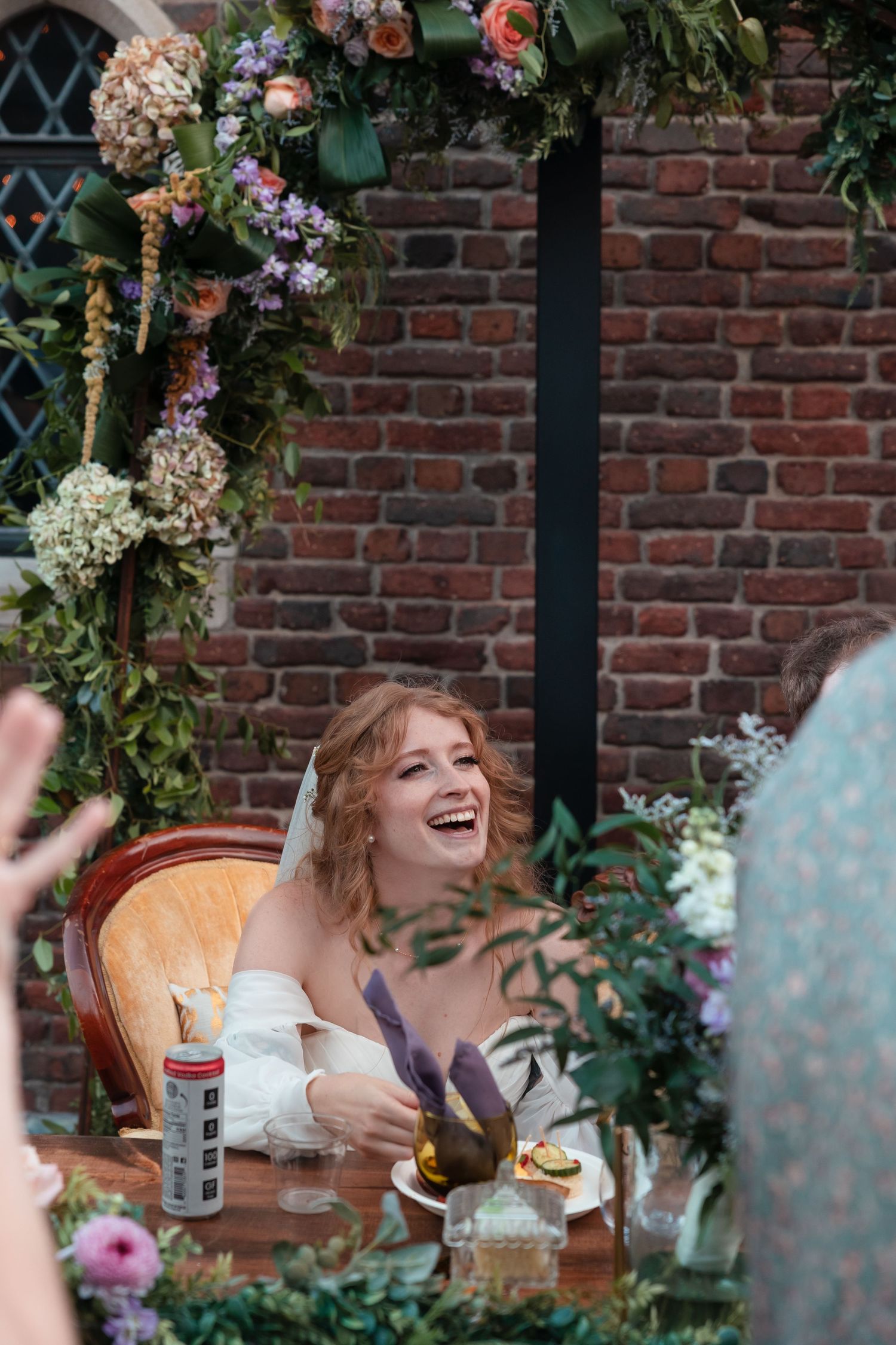 Wedding reception setup with floral arrangements decorating a rustic brick wall backdrop.