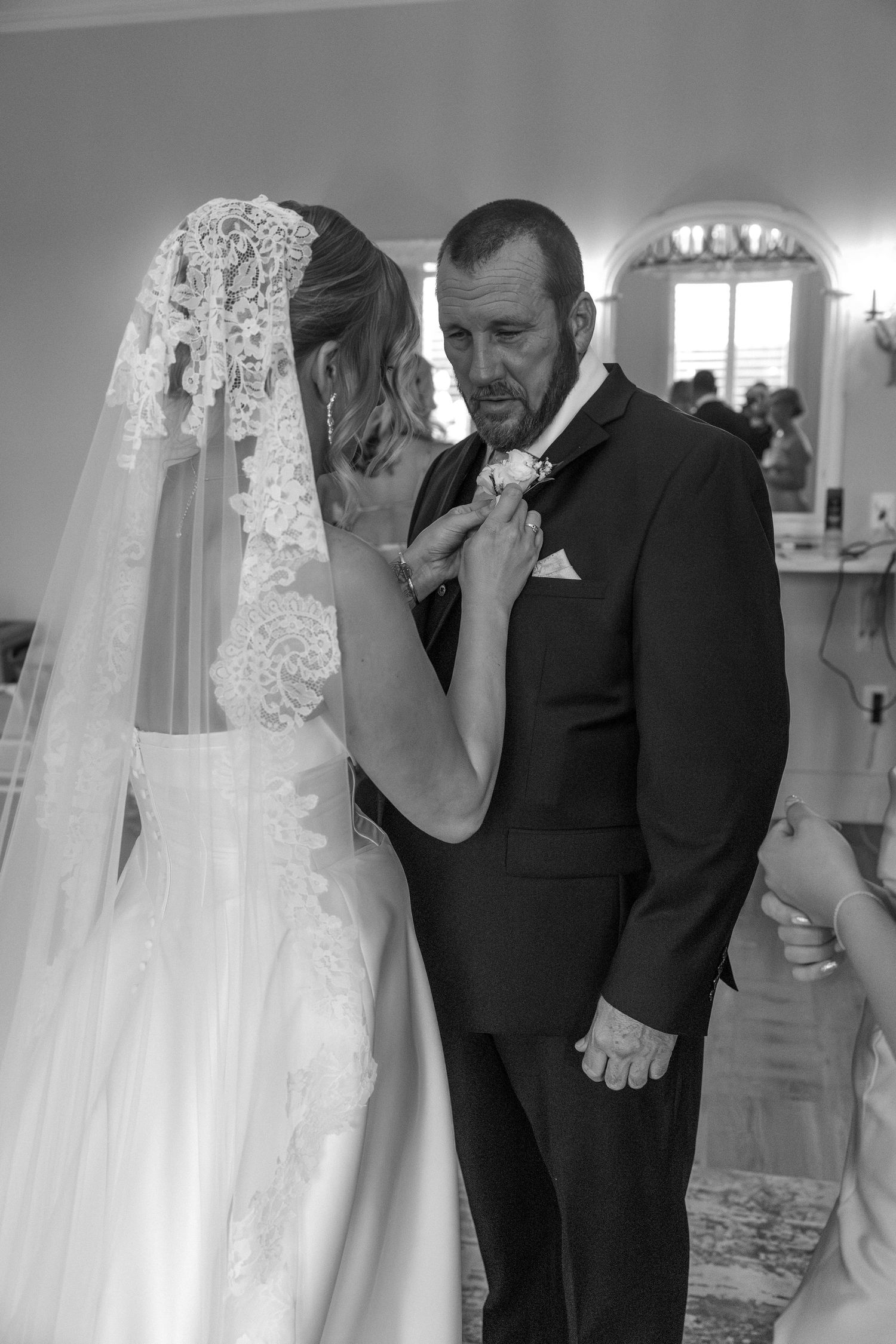An emotional black and white moment between a bride and someone in a suit during a wedding ceremony.