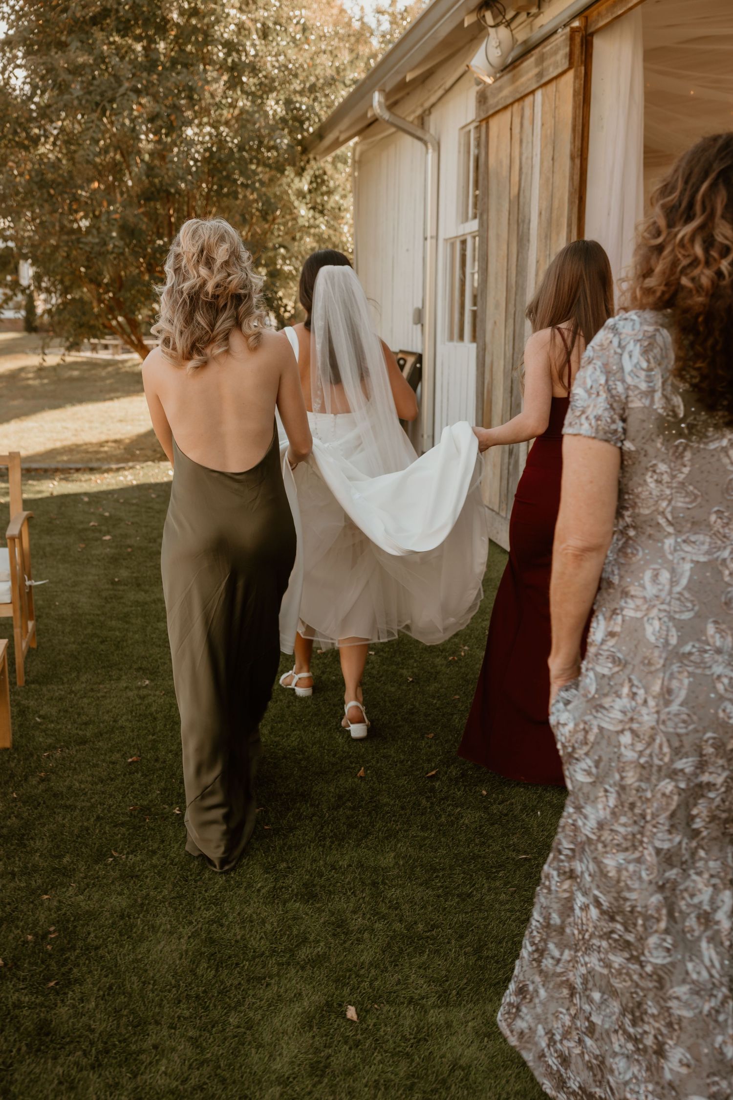 Wedding party walking together on grass in formal attire.