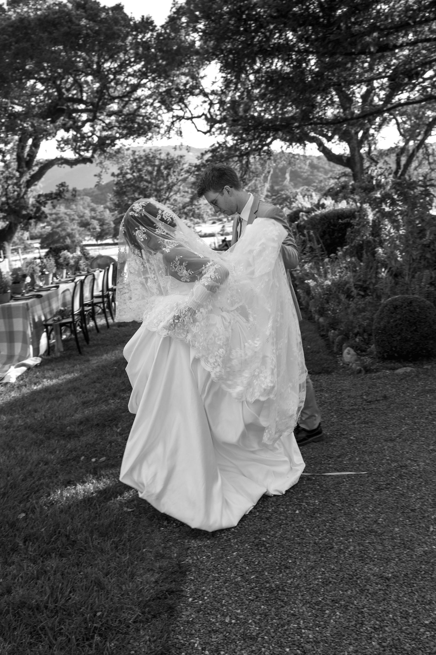 A sequence of black and white photos showing a couple in wedding attire running playfully down a grassy hill.
