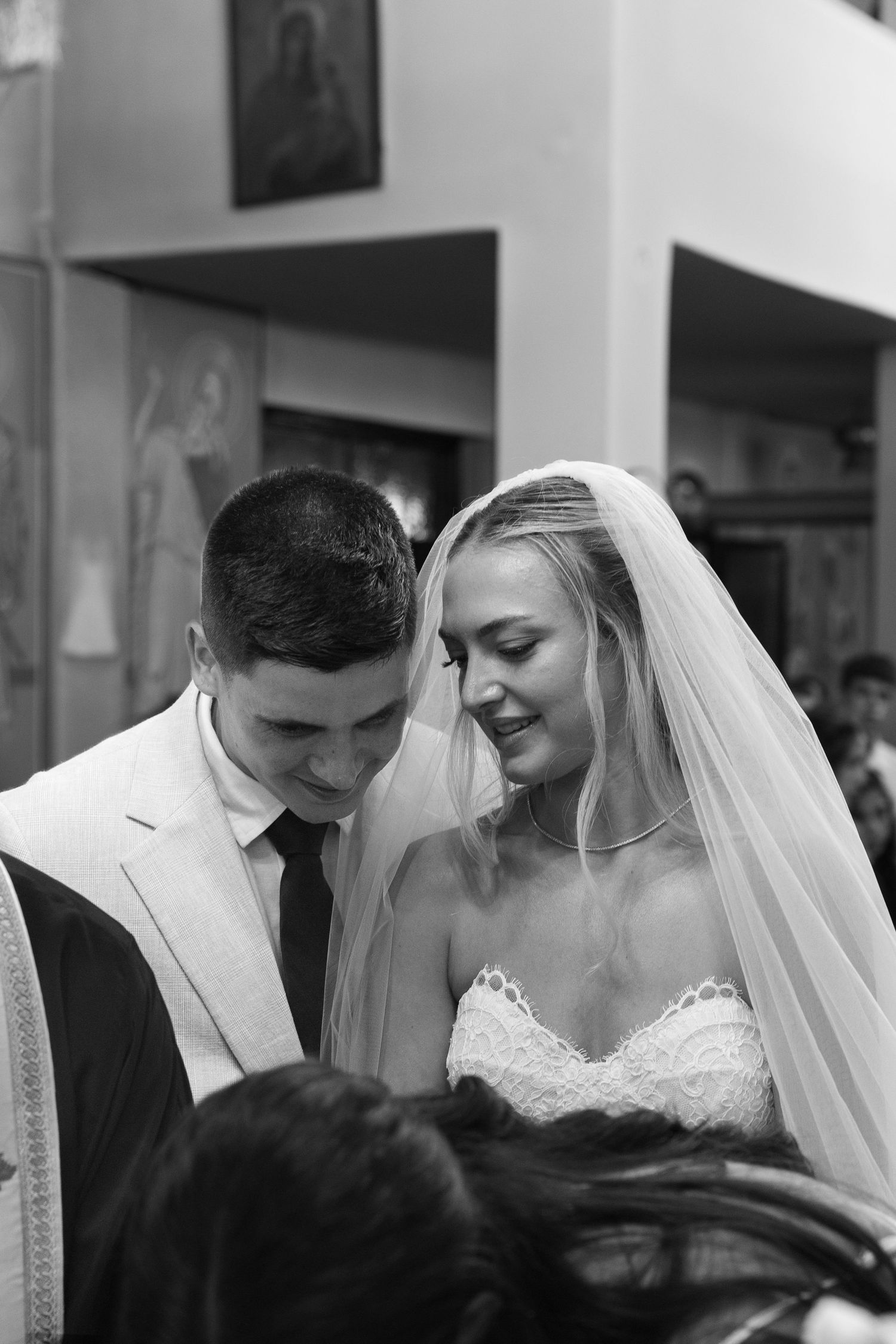 Black and white wedding photograph showing tender moment between newlyweds during their ceremony.