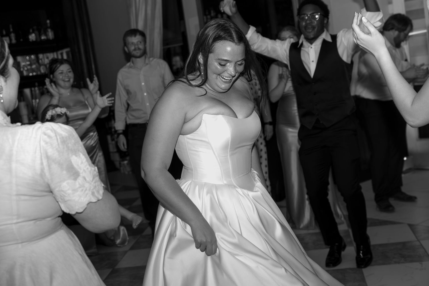 Wedding guests dance and celebrate on a crowded dance floor at an indoor reception.
