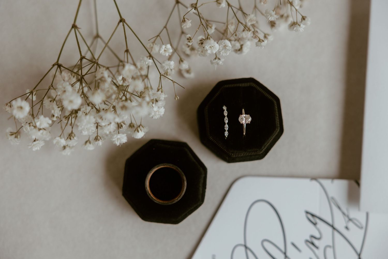 Two black octagonal ring boxes with dried baby's breath flowers against a white background.