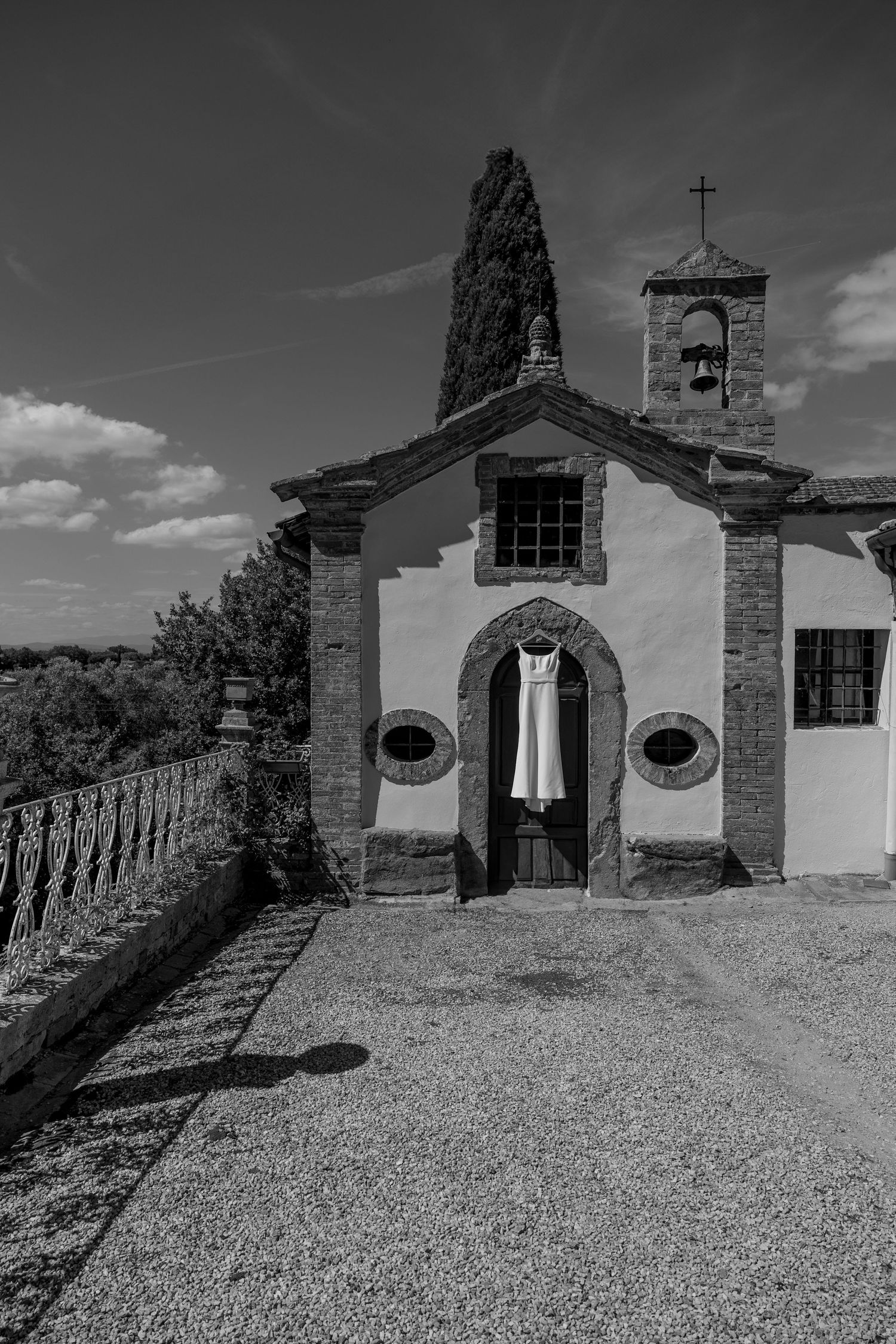 Historic stone church buildings line a gravel path under dramatic black and white sky.