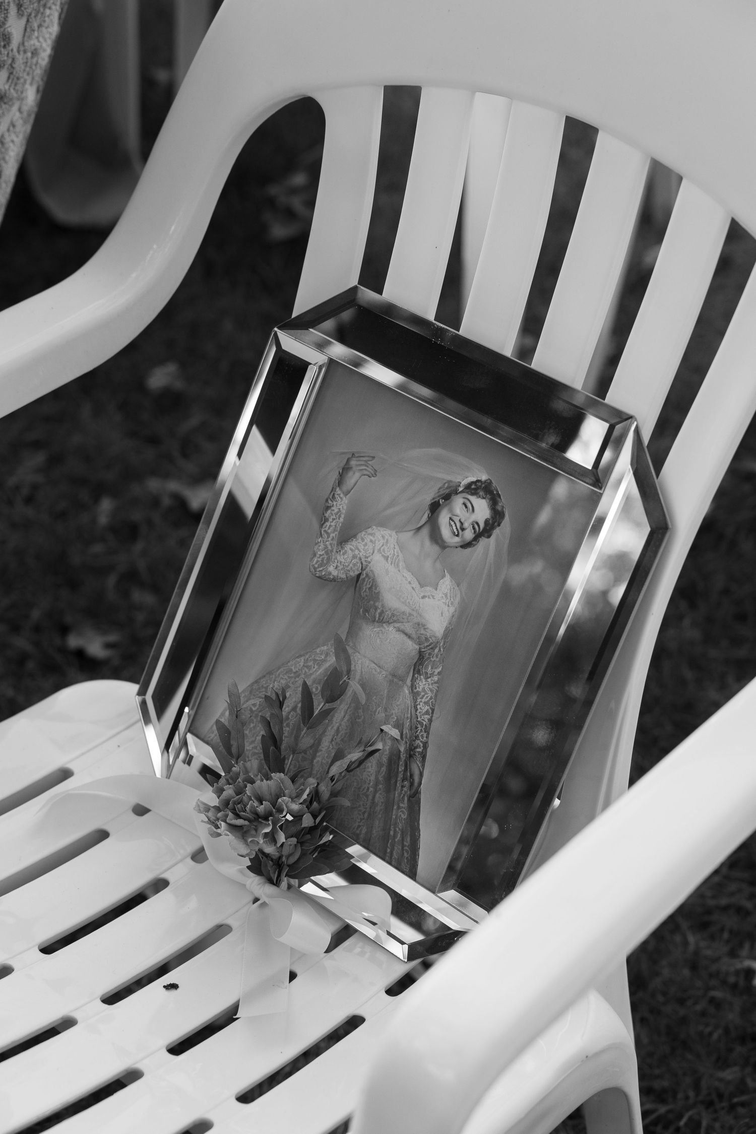A series of black and white photographs displayed on white chairs in an artistic arrangement.