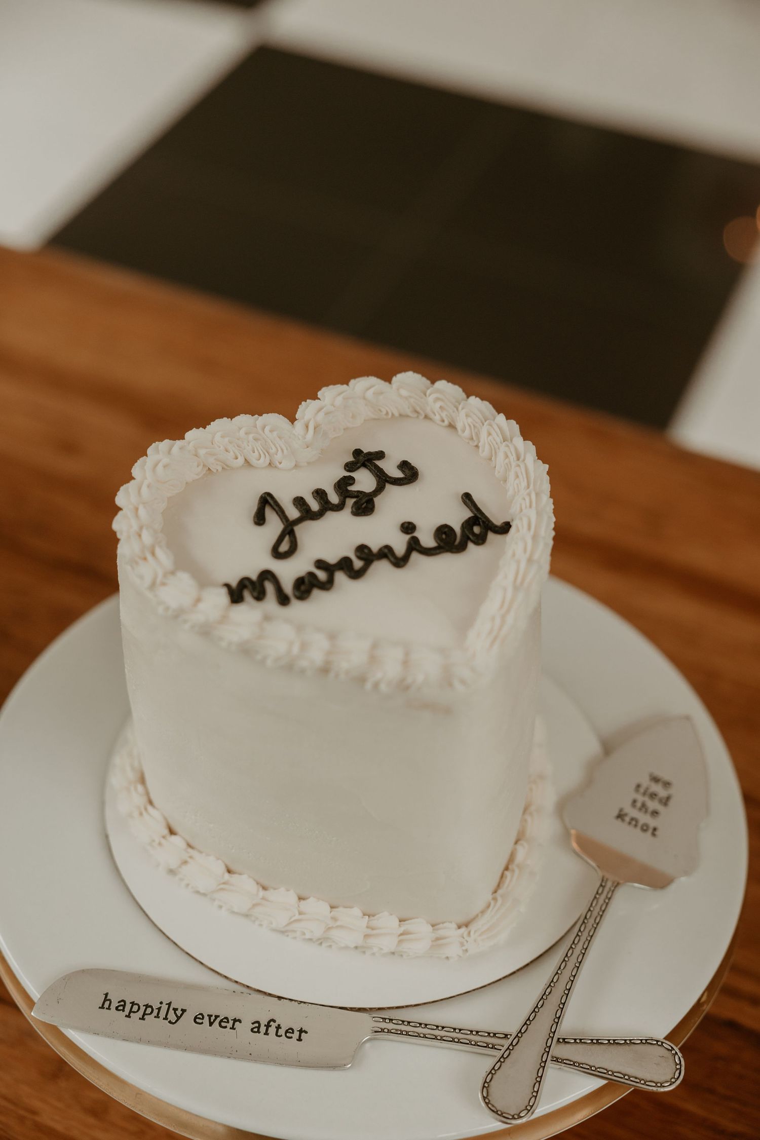 A simple white wedding cake with delicate piping details on a wooden table.
