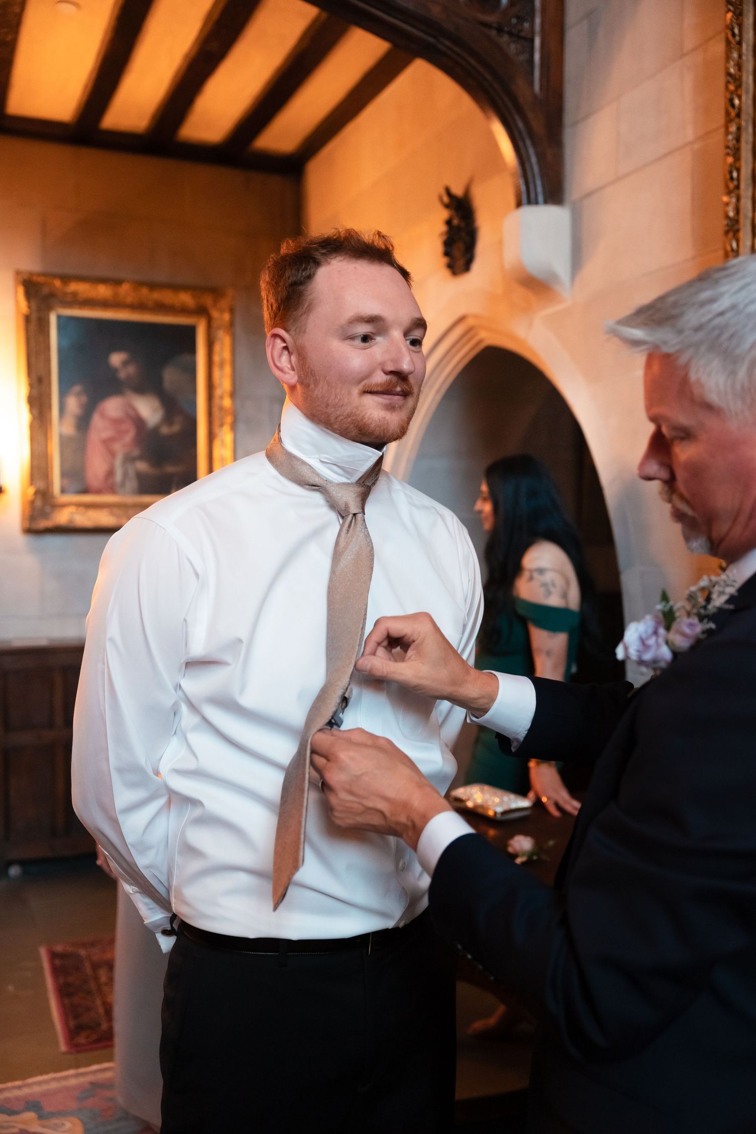 Progressive shots of a groom getting help with his tie and formal attire before the ceremony.