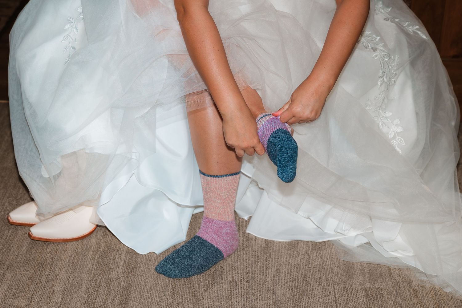 A person in a white wedding dress puts on blue socks in a sequence of four photos.
