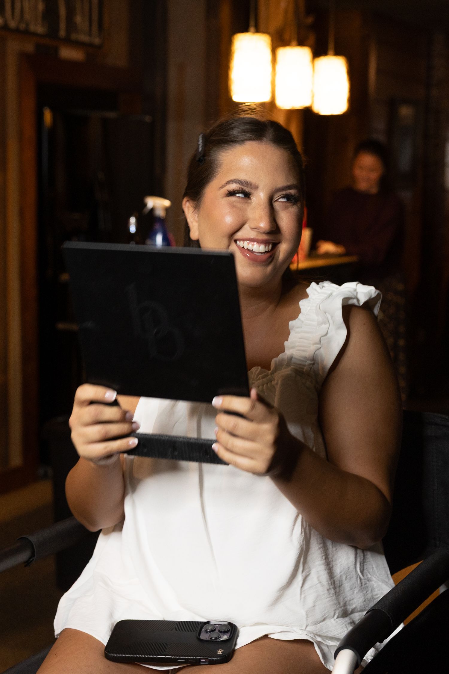 A series of candid photos showing someone laughing while holding and tearing paper in a dimly lit room.