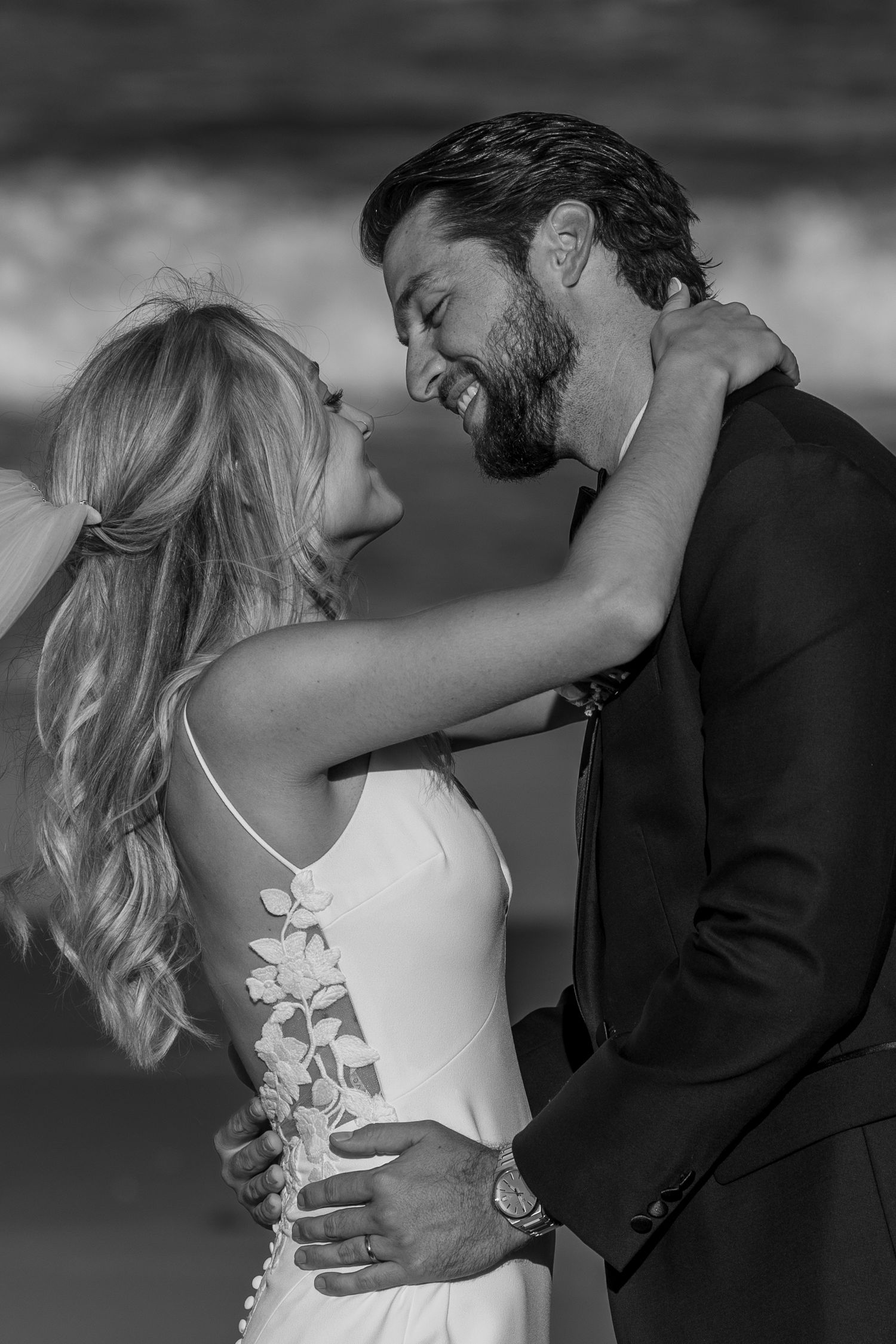 Intimate black and white portrait of newlyweds sharing a tender moment in elegant wedding attire.