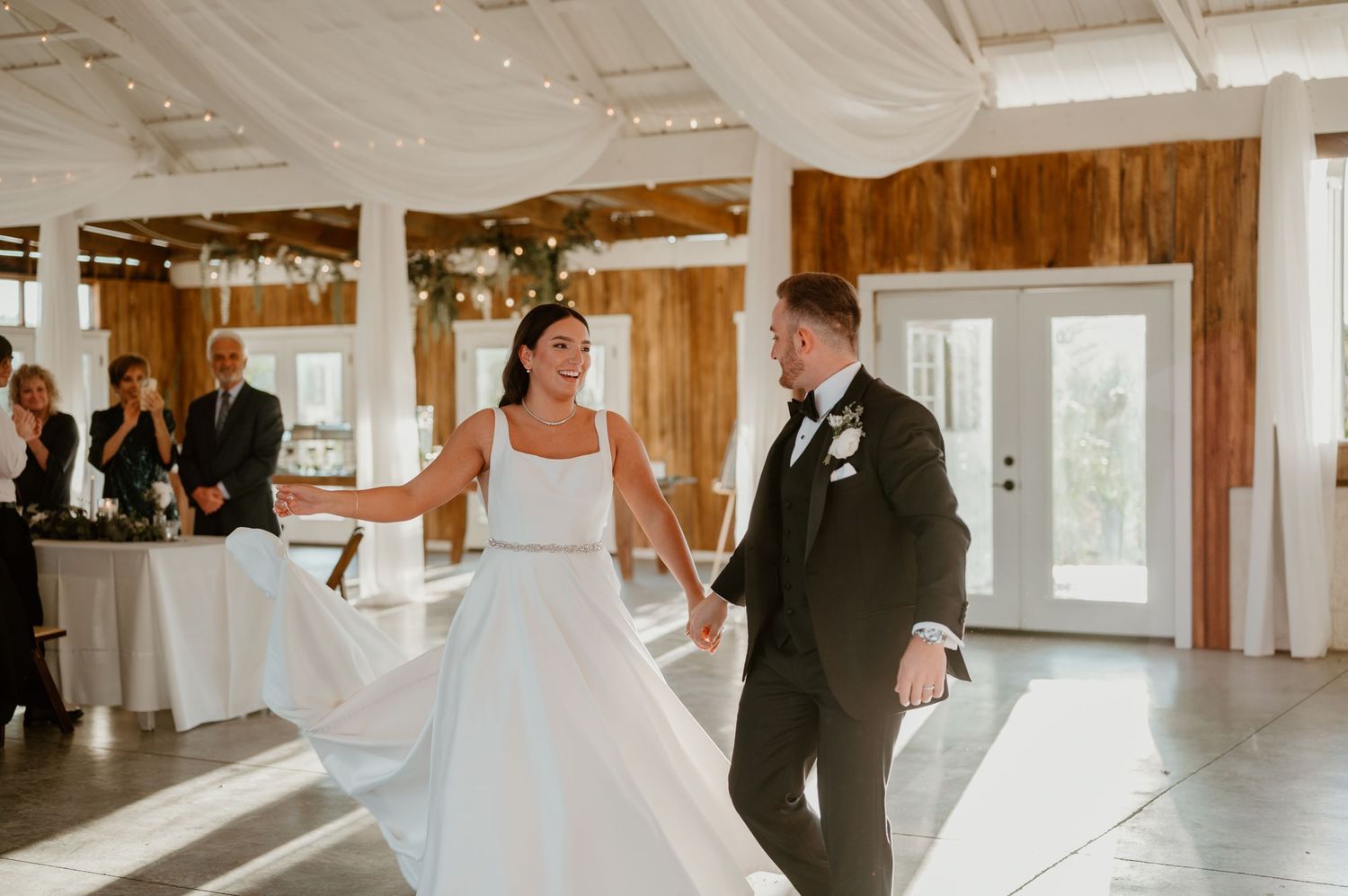 Wedding couple dancing together in an elegant bright indoor venue with rustic decor.