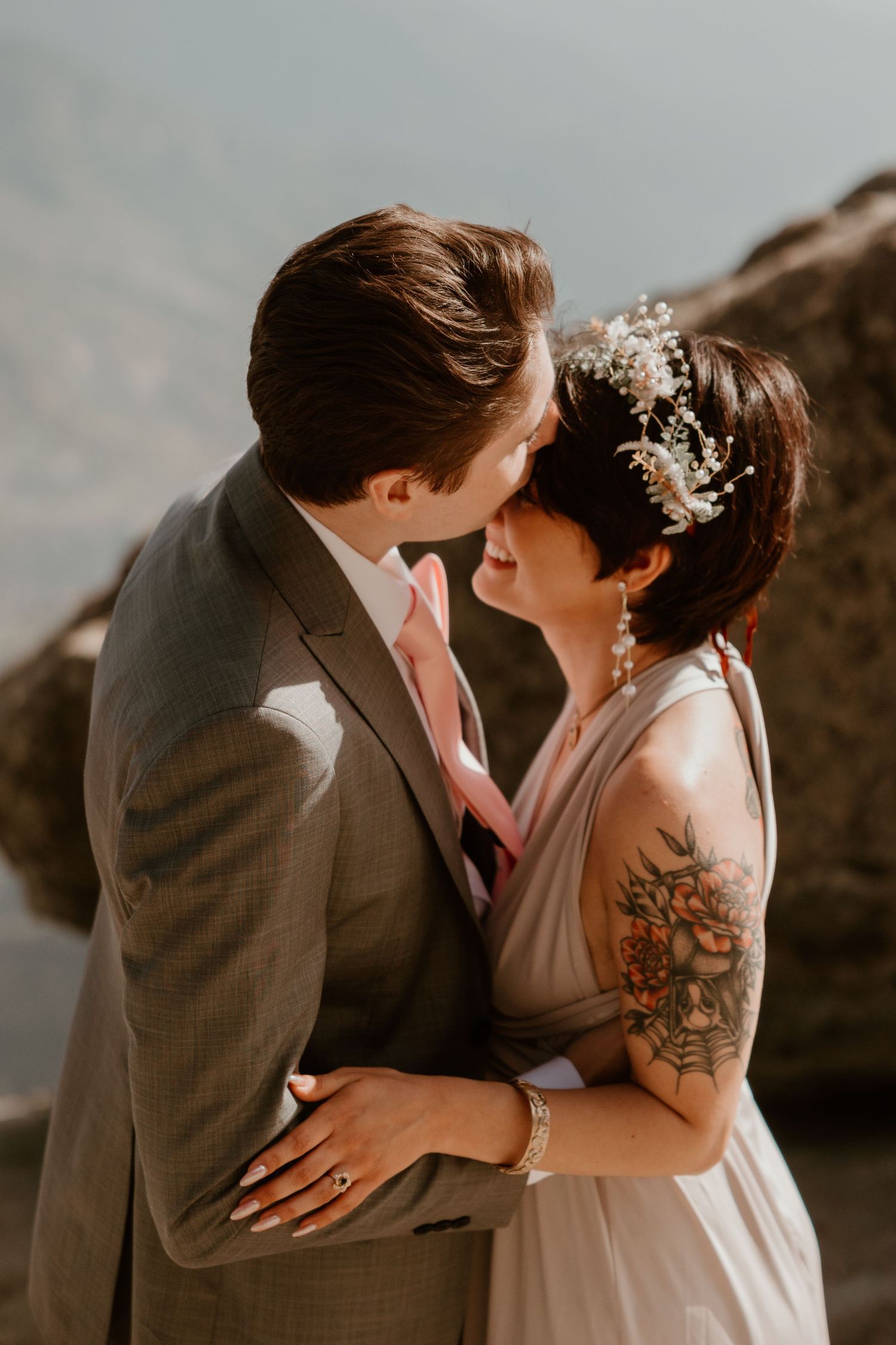 A tender moment between newlyweds against a mountainous backdrop at sunset.