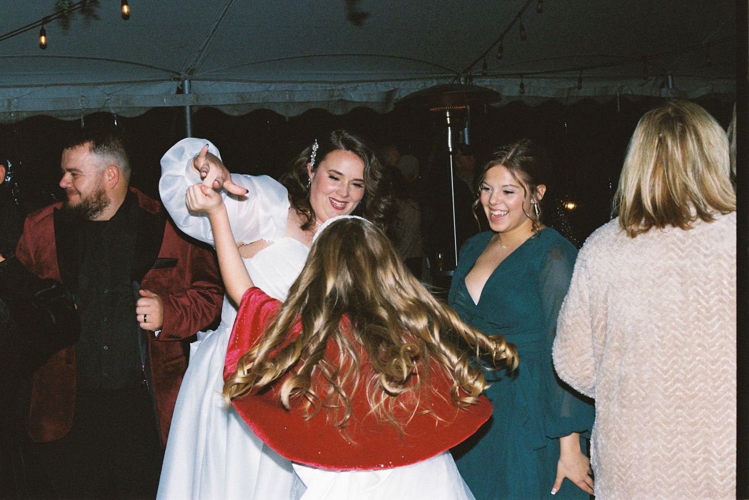 Reception guests dancing and celebrating on the dance floor under party lights.