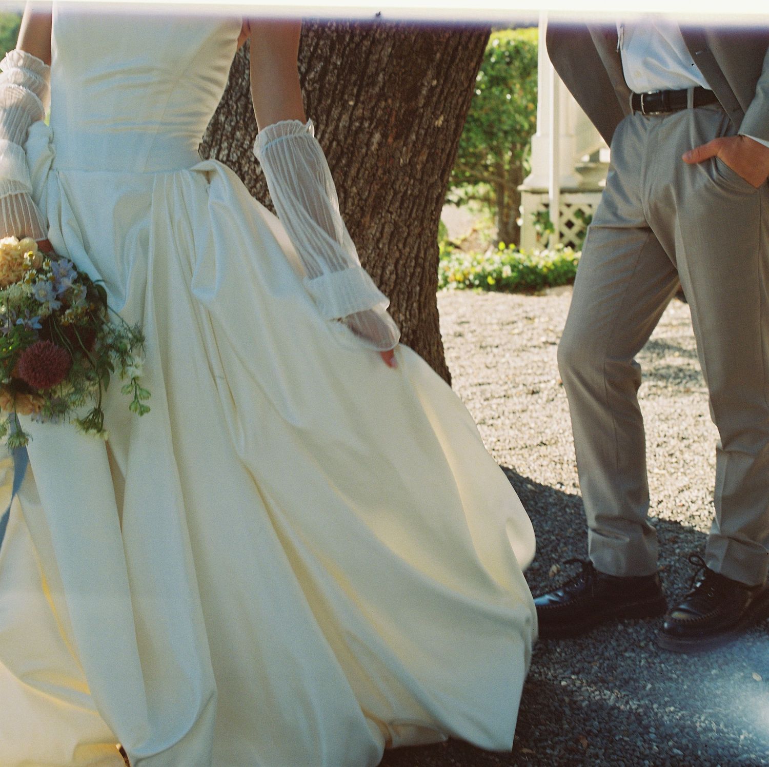 Bride and groom's feet walking together on a gravel path during an outdoor wedding ceremony.