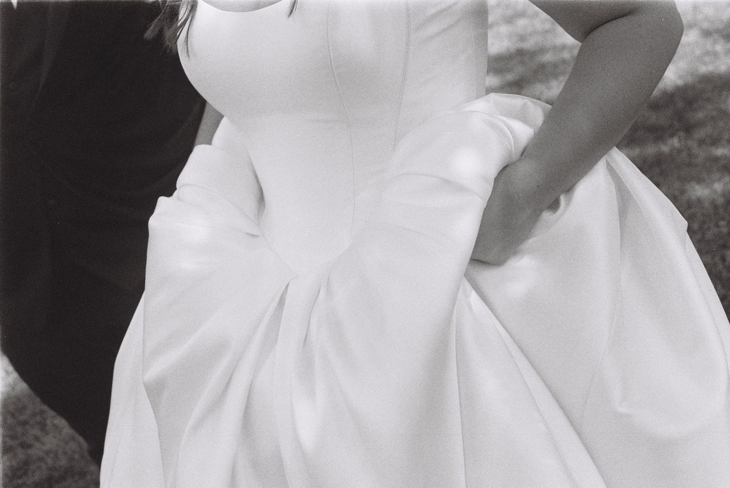 A collection of wedding dress details showing white fabric, bows, and elegant embellishments in a black and white photo.