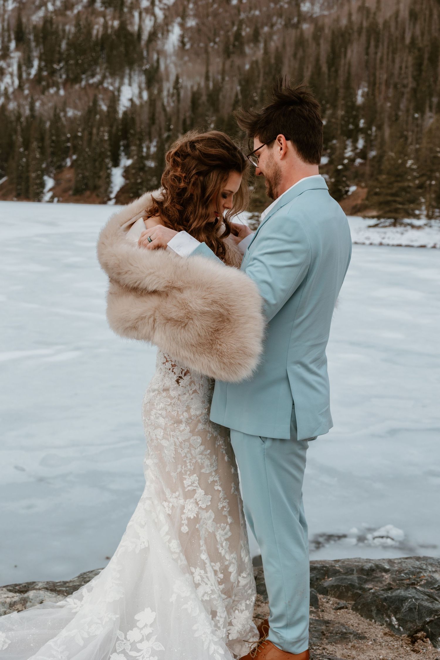 A romantic winter wedding moment captured against a snowy mountain backdrop.