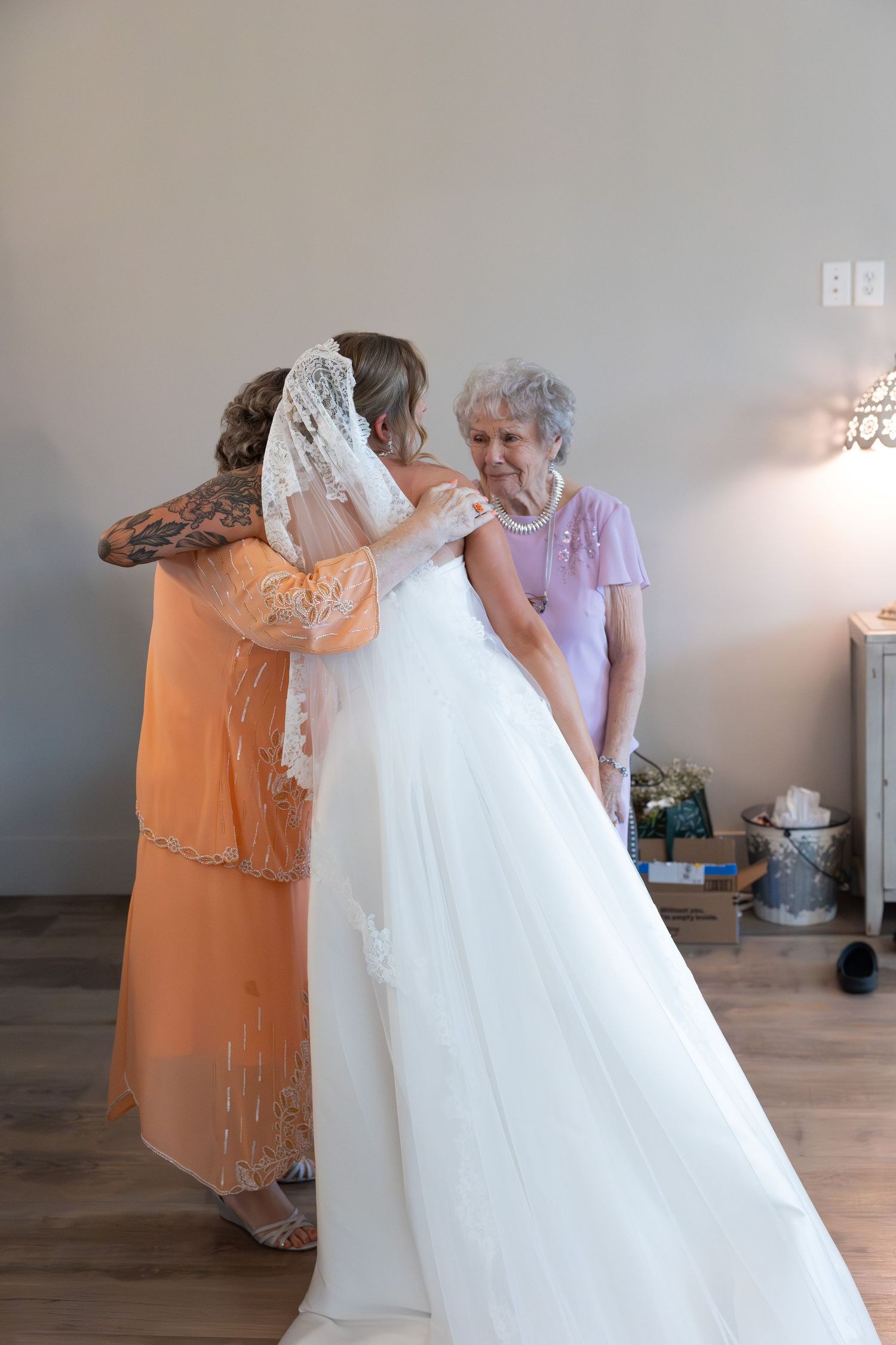 A tender moment during wedding preparations as family members assist with the bridal gown.