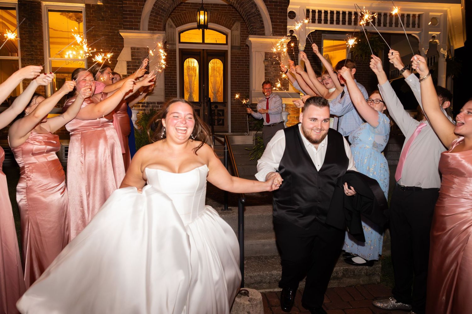 Wedding reception dance floor filled with guests celebrating in formal attire and pink dresses.