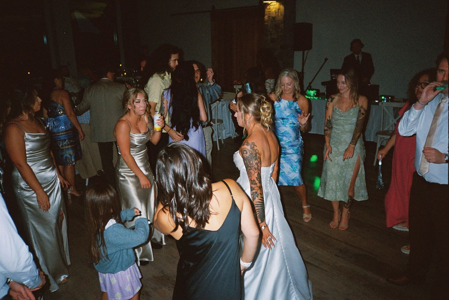 Dark reception party scene with dancing guests illuminated by ambient lighting.